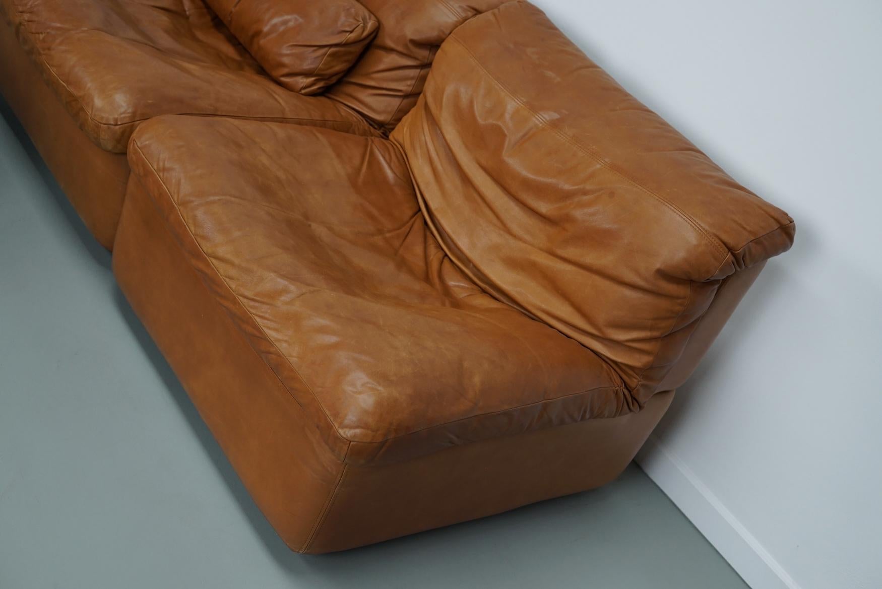This vintage modular sectional sofa was manufactured by Rolf Benz in Germany around the 1970s. It is upholstered in cognac leather and which has retained a beautiful patina over the years. It is very comfortable and the leather is very soft to the