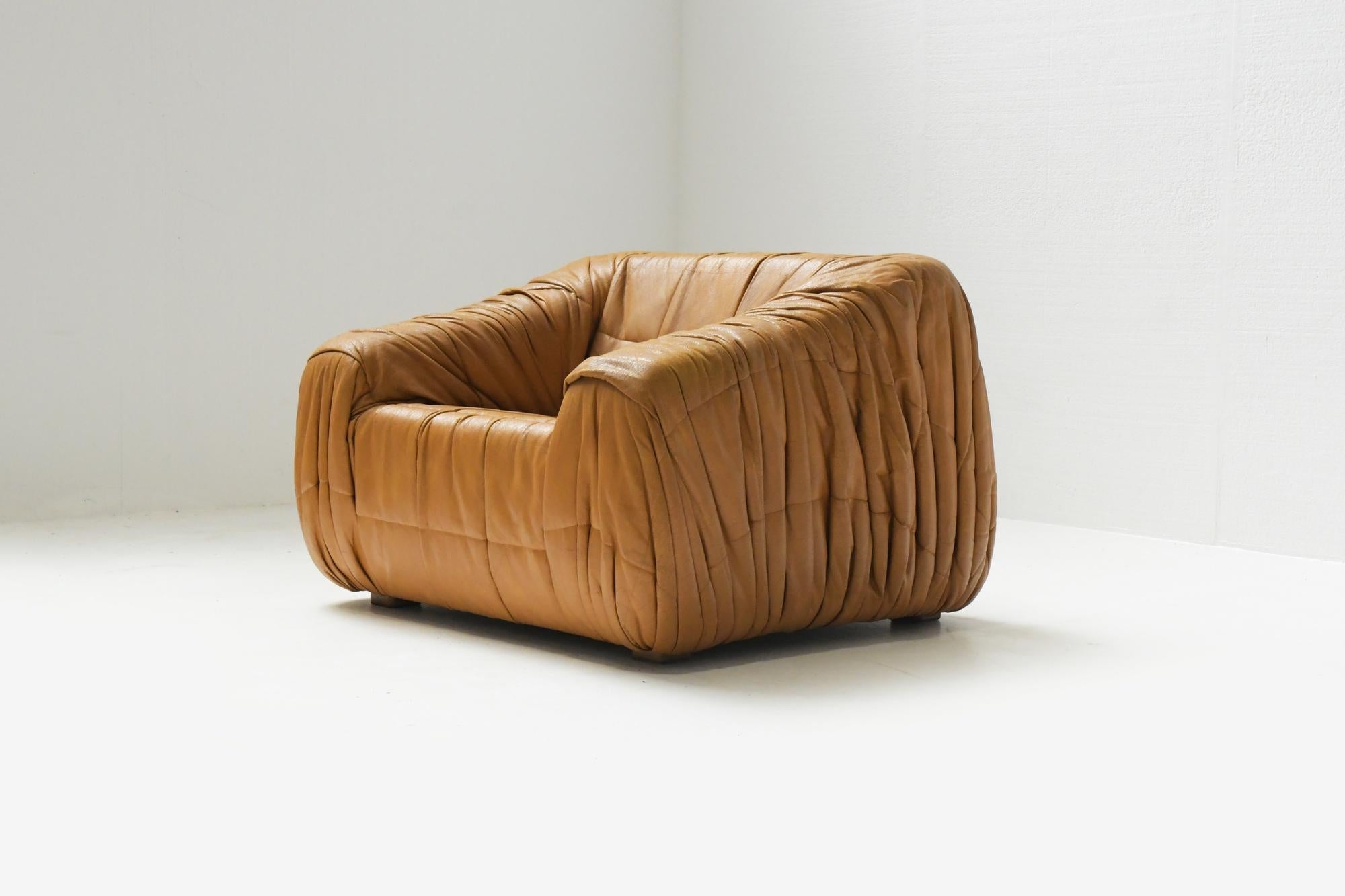 Fantastic ‘Piumino’ lounge chair designed by the Milanese architect trio De Pas, D’urbino and Lomazzi and manufactured by Dall’Oca, Italy, 1970. 
The chair has an ultra soft cognac faux leather upholstery with a stunning wrinkled stitching