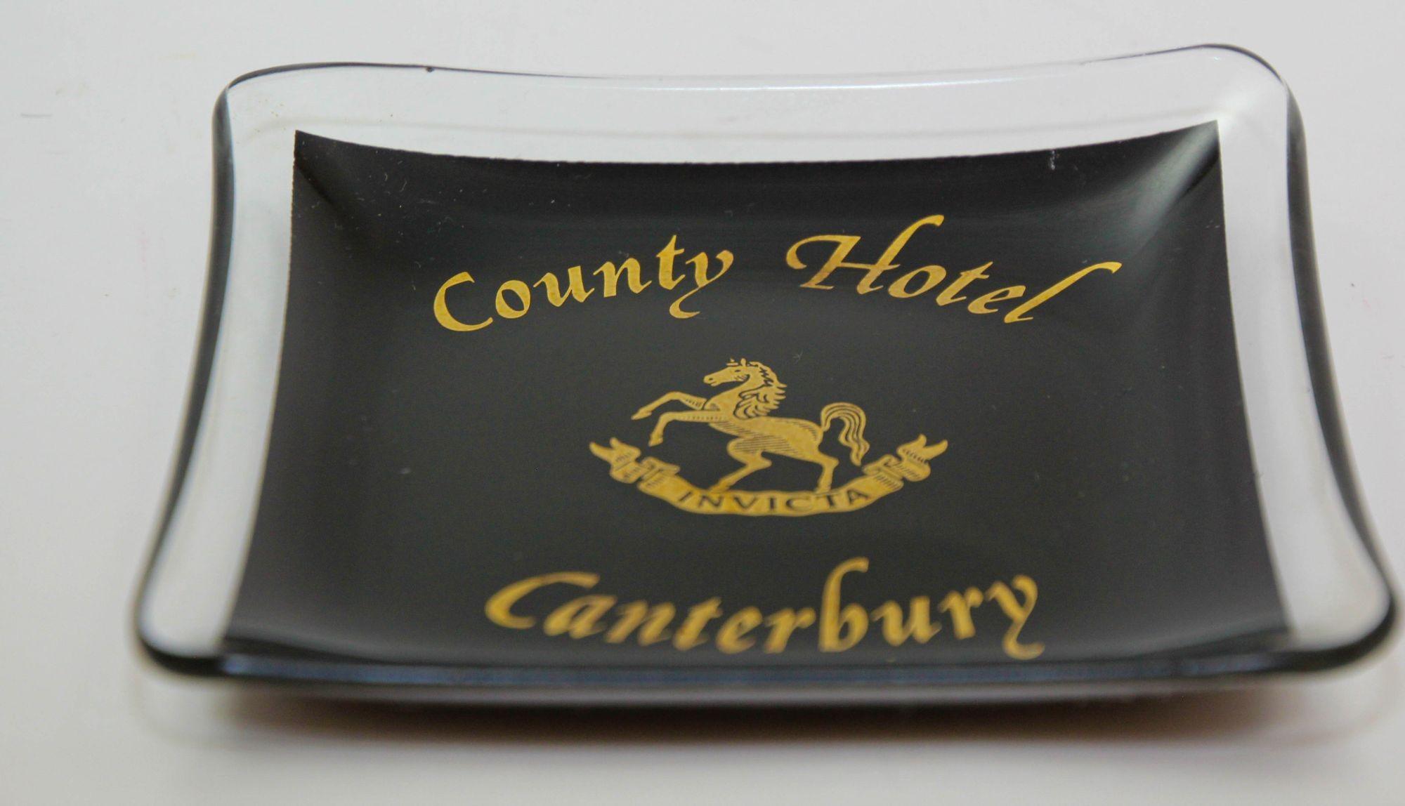 Vintage Collectible Dish County Hotel Canterbury England 1960s.
Jewellery, Pin Dish, Ashtray, Glass dish in black and gold design of a horse in the middle on a banner inscribed with INVICTA and County Hotel Canterbury.
Vintage advertising
