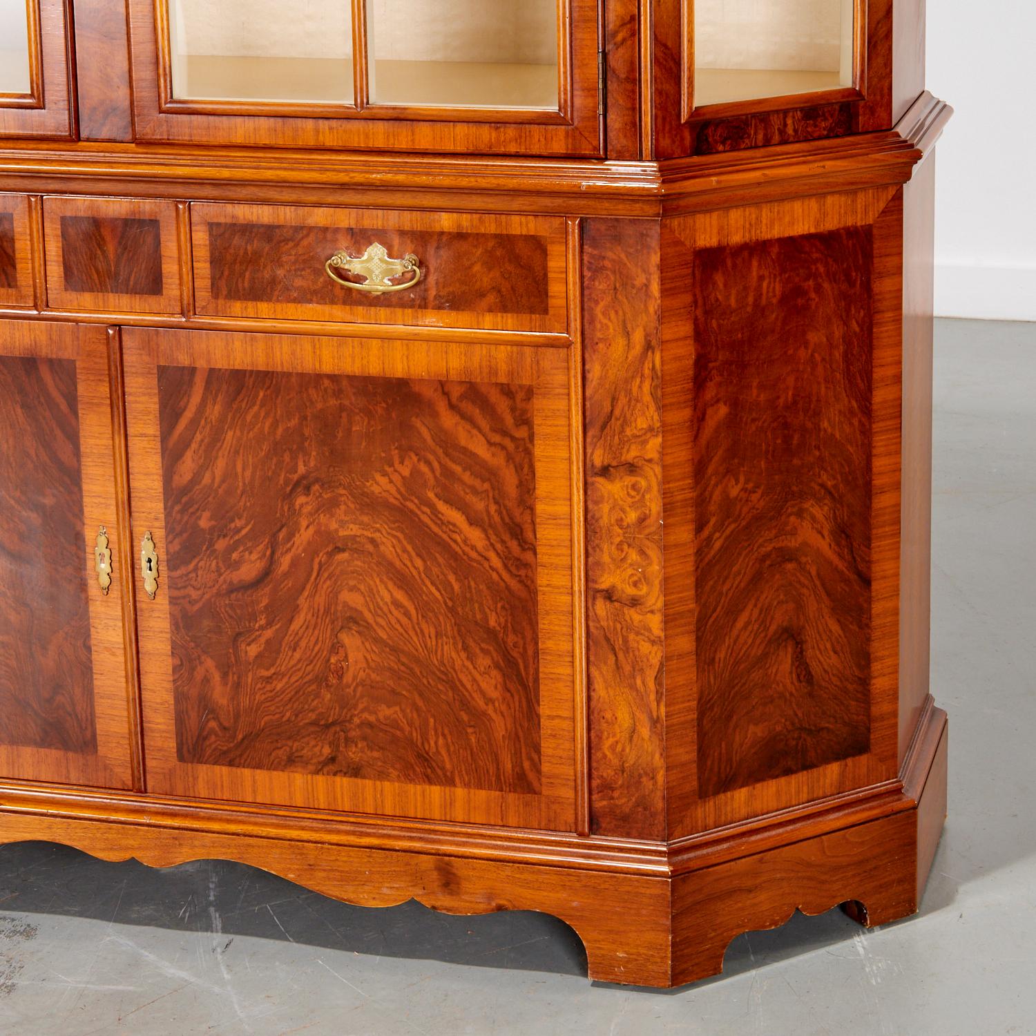 20th c. a stunning display cabinet that combines both aesthetic appeal and functionality, perfect for any elegant home or collector's space. This cabinet is a striking example of craftsmanship, made from rich, highly-figured walnut veneer with