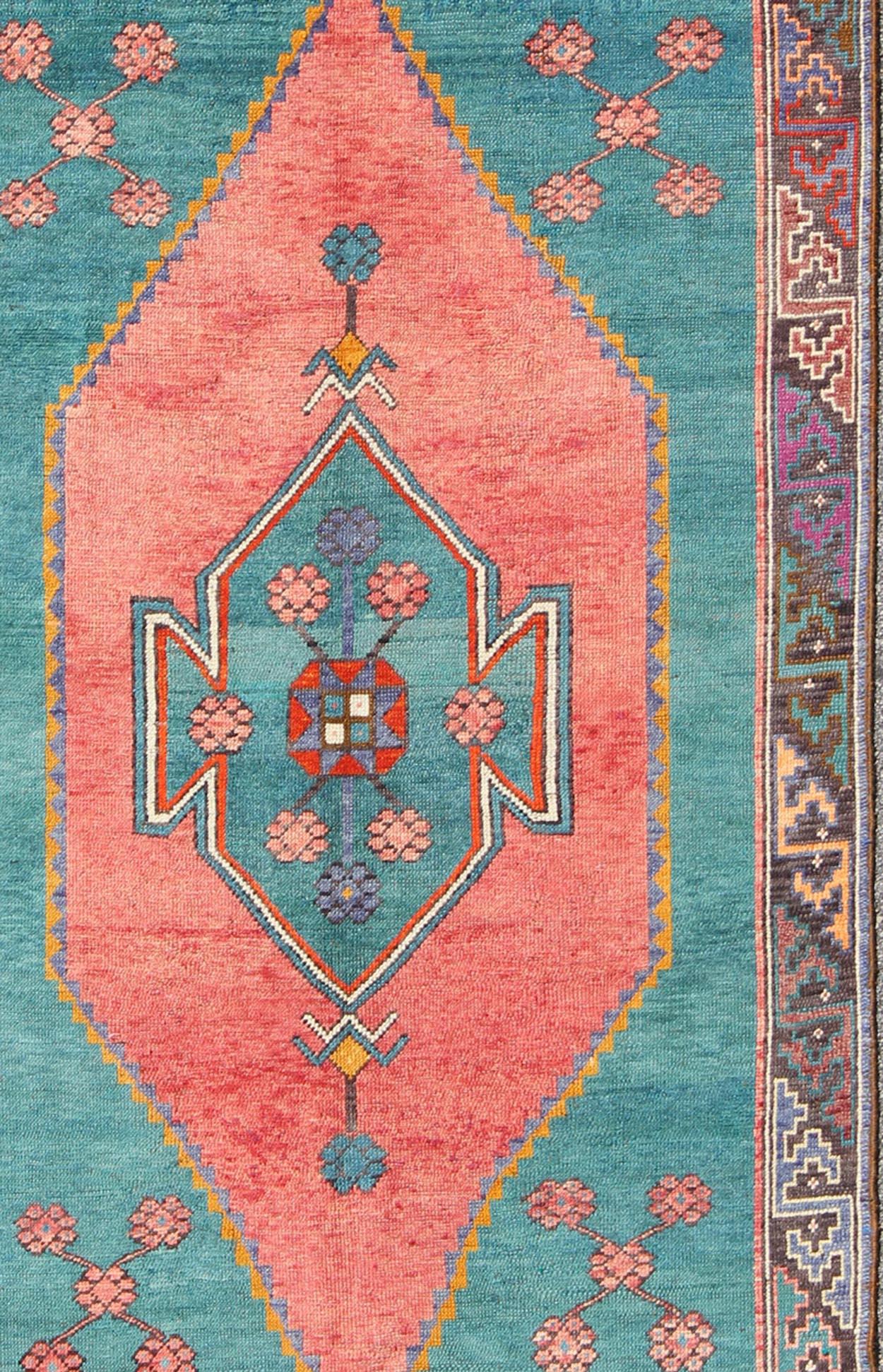 Colorful Turkish medallion with tribal design in teal, coral, background and complemented by deep multi colors in the repeating geometric motif consist of  charcoal Gary,  brown, purple, yellow, gray, light blue ivory, green border, rug