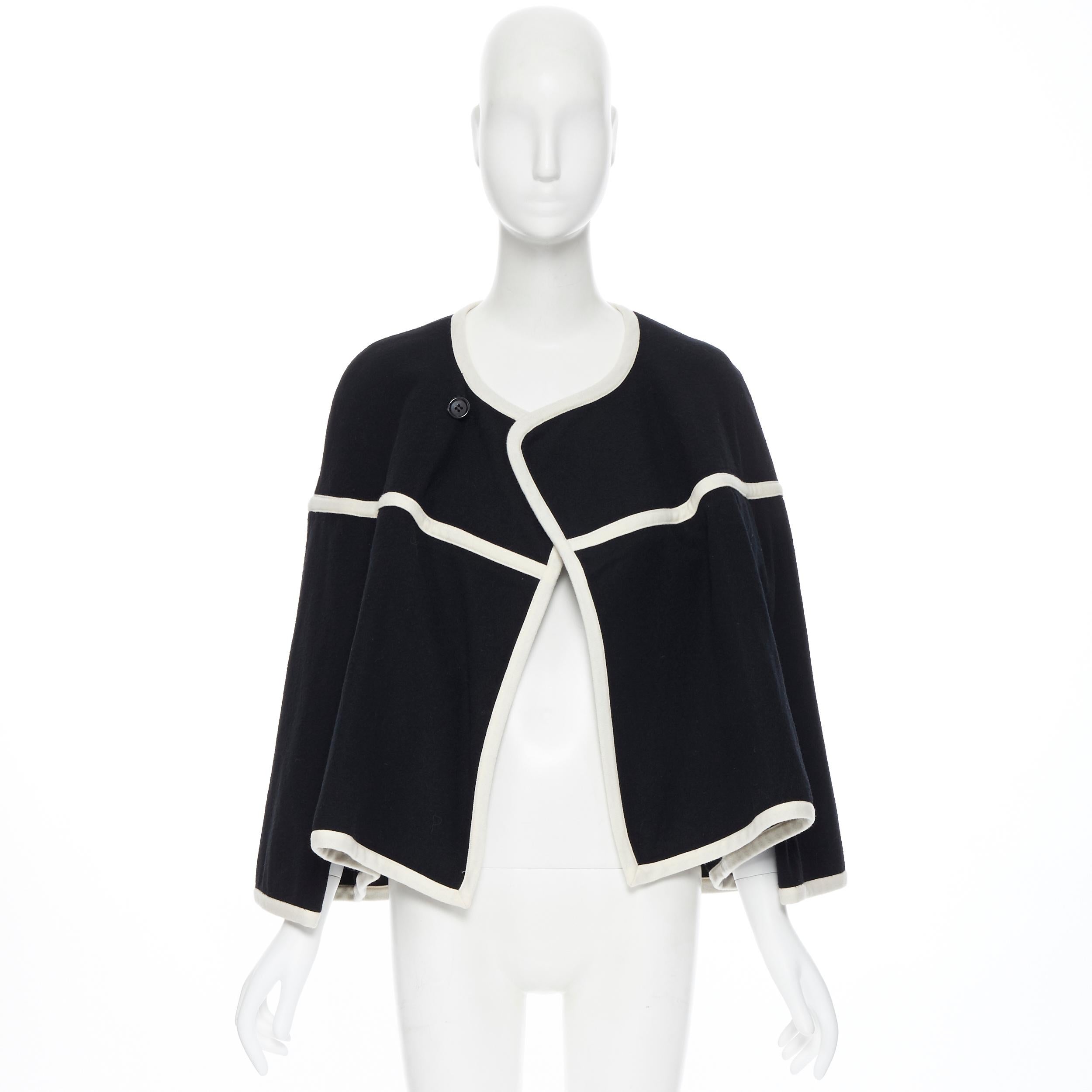 vintage COMME DES GARCONS 1989 Runway black white trimmed cape poncho jacket M 
Reference: CRTI/A00258 
Brand: Comme Des Garcons 
Designer: Rei Kawakubo 
Collection: 1989 Runway 
Material: Wool 
Color: Black 
Pattern: Solid 
Closure: Button 
Extra