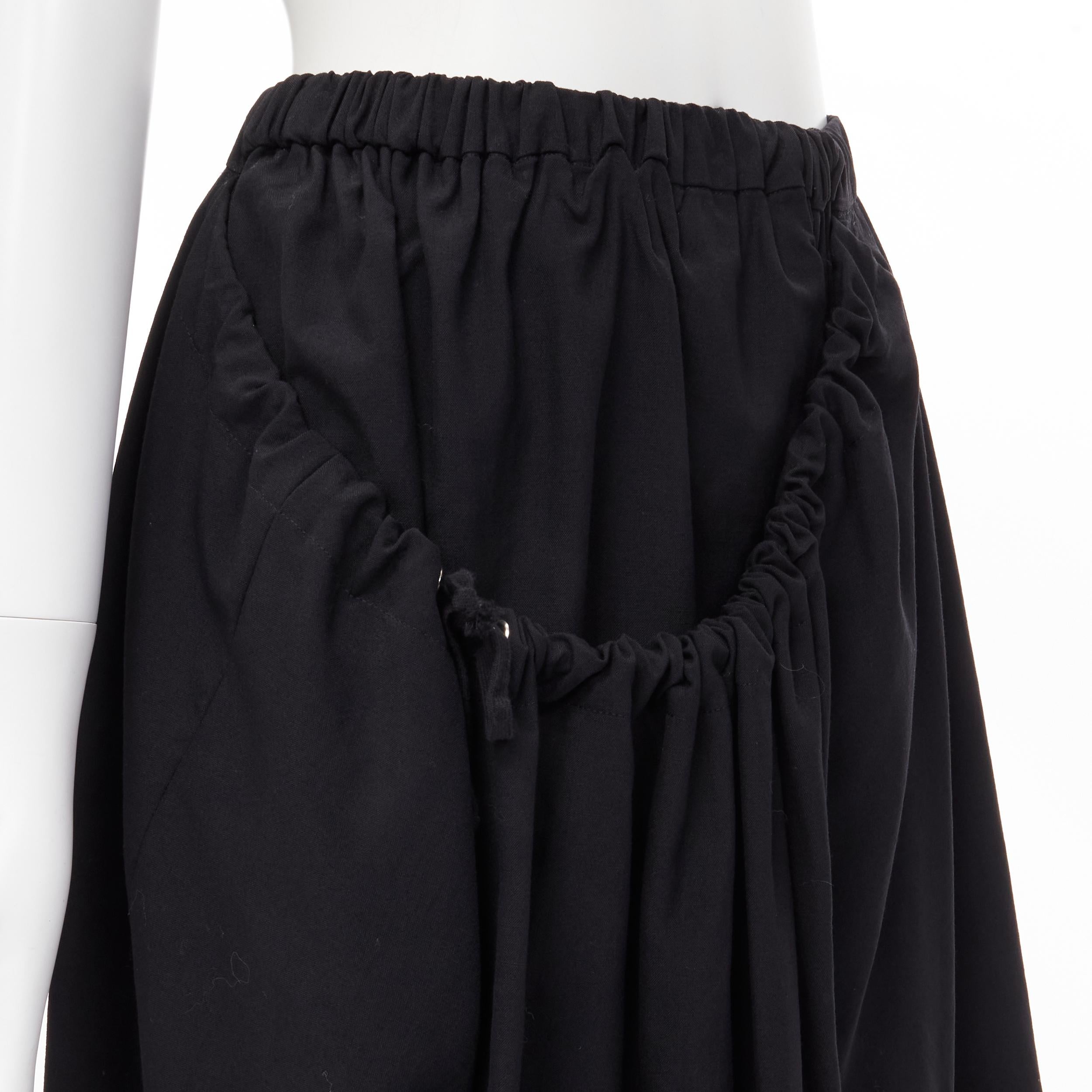 vintage COMME DES GARCONS 1990 black draped faux pocket asymmetric skirt M 
Reference: CRTI/A00355 
Brand: Comme Des Garcons 
Designer: Rei Kawakubo 
Collection: 1990 
Material: Wool 
Color: Black 
Pattern: Solid 
Extra Detail: Elasticated waist.