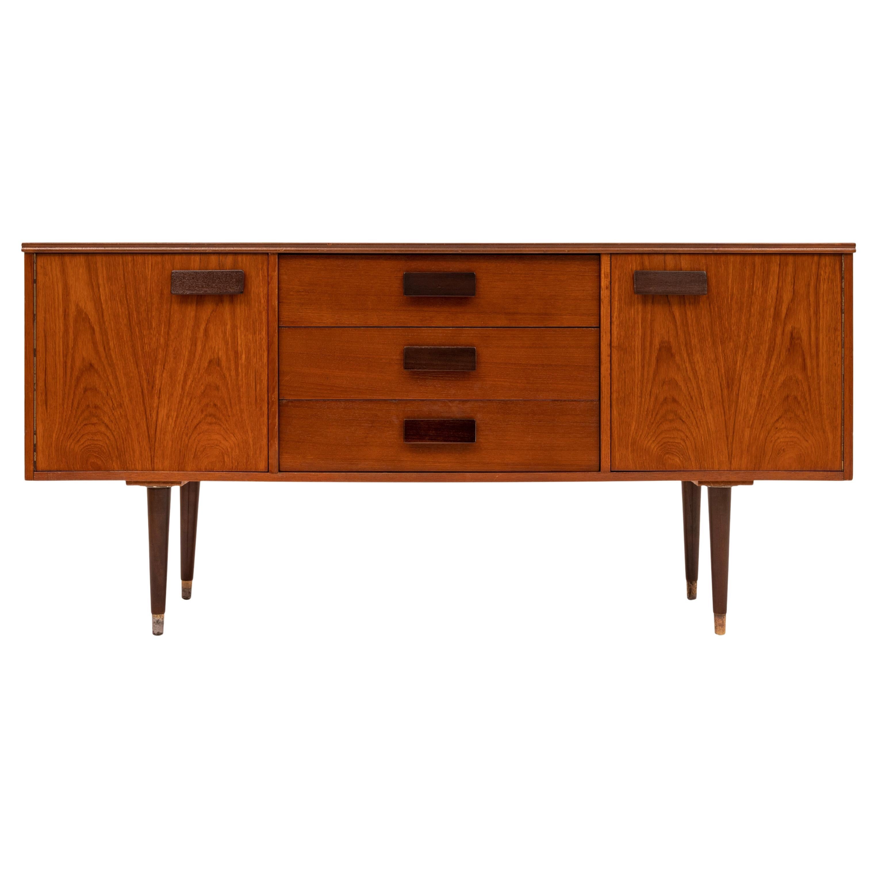 A good vintage Mid-Century Modern teak credenza/sideboard, 1960s.
The credenza of unusual compact and bijou Size and having twin cupboards at each end, the cupboard to the right side is fitted with a single shelf. To the middle is a bank of three