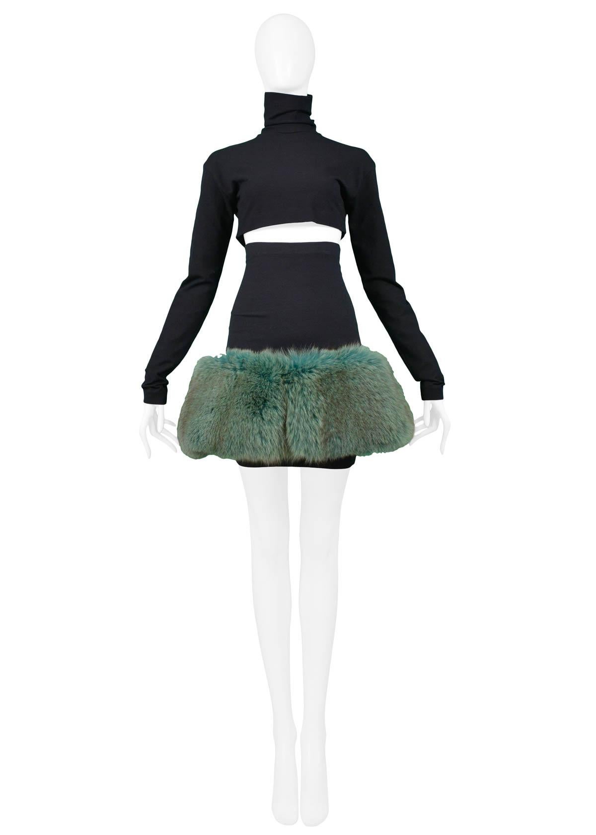 Vintage Complice black wool knit top and skirt ensemble. The set features a long sleeve high neck crop top with center back zipper closure and high waisted mini skirt adorned with jade green colored mink at hem. Runway piece from the 1991