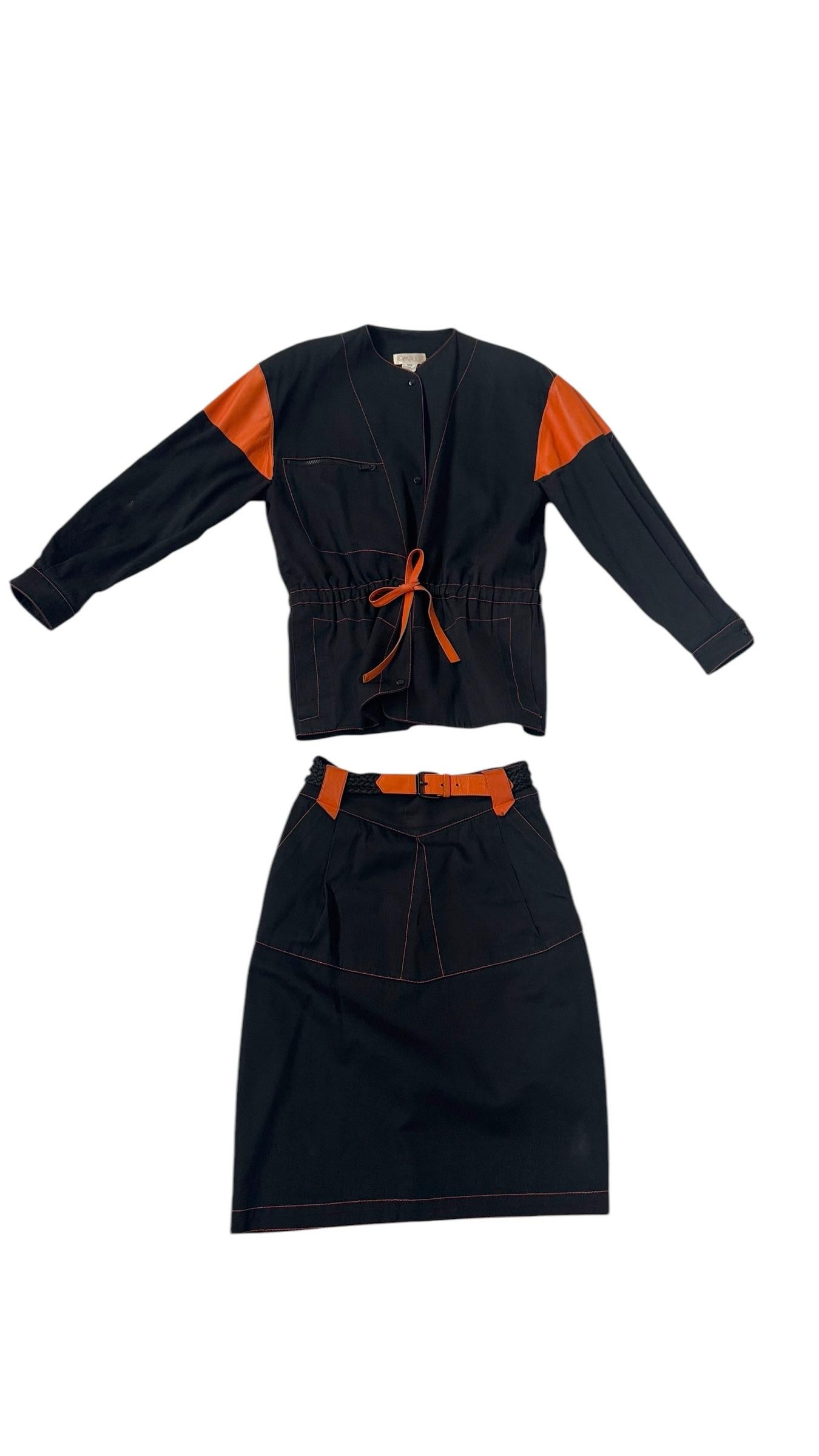 Extremely rare vintage two-piece ensemble by Complice, likely from the late 1970s to early 1980s, featuring structured black cotton fabric with bold orange leather inserts on the shoulders, waistband, and pockets. The set includes a minimal,
