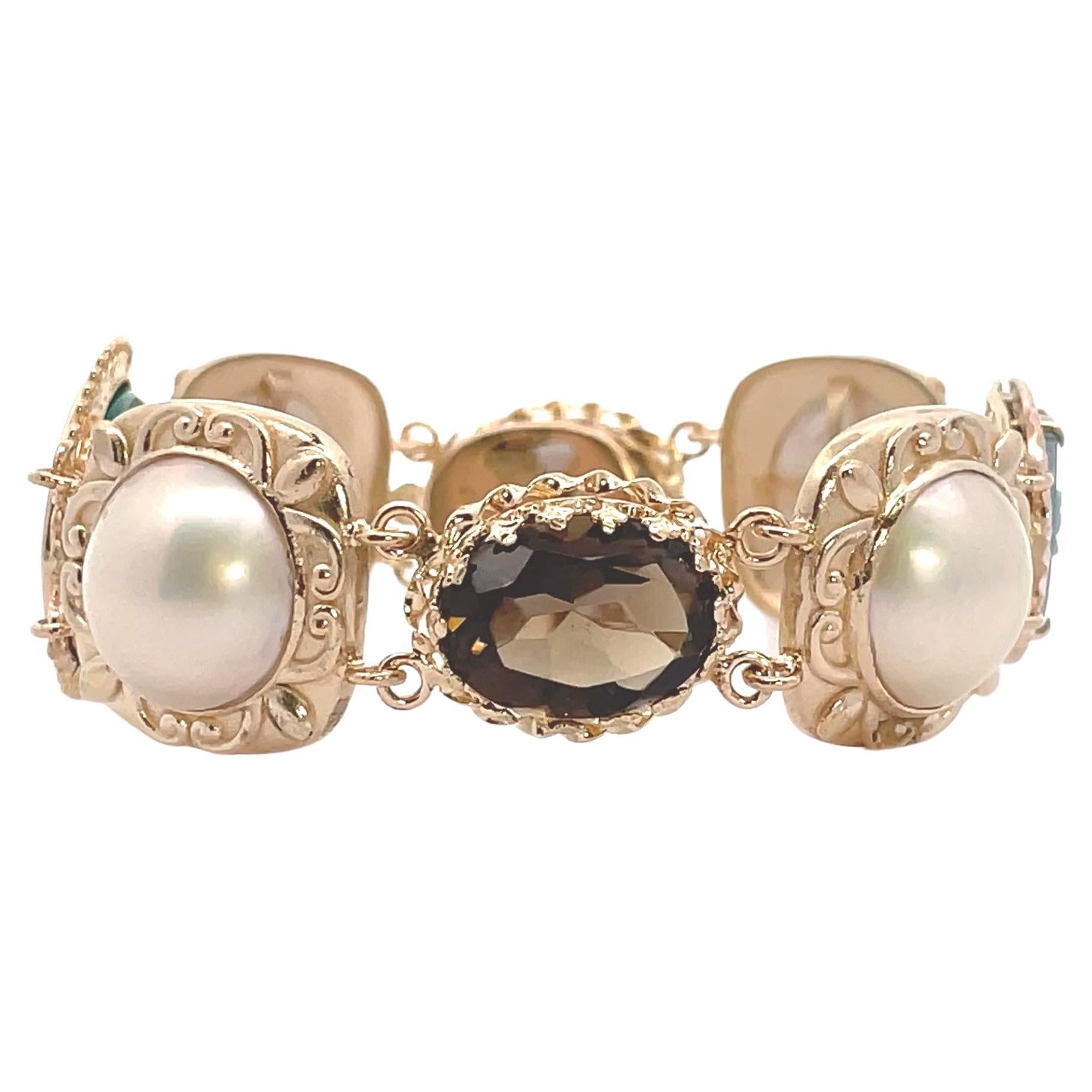One of a kind 14K yellow gold bracelet composed of vintage components. The bracelet features 4 mobe pearls, two cameos and two oval shape smokey topaz.  One cameo is carved from green onyx depicting the profile of a woman and the other cameo is