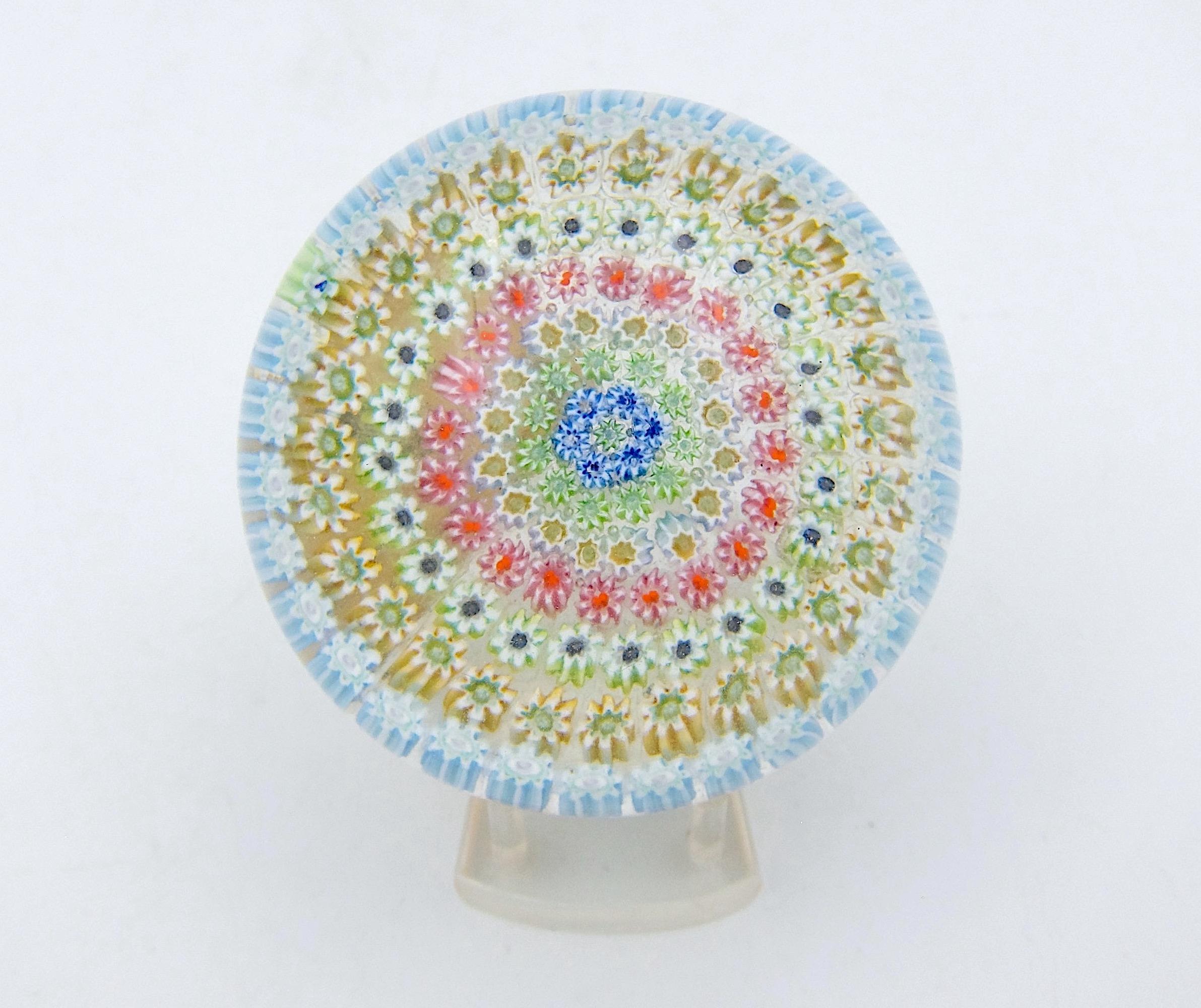 A vintage millefiori art glass paperweight, handcrafted by Perthshire Paperweights, Ltd. of Crieff, Scotland and dating to the last quarter of the 20th century. The medium-sized, domed weight features a a central cane surrounded by seven