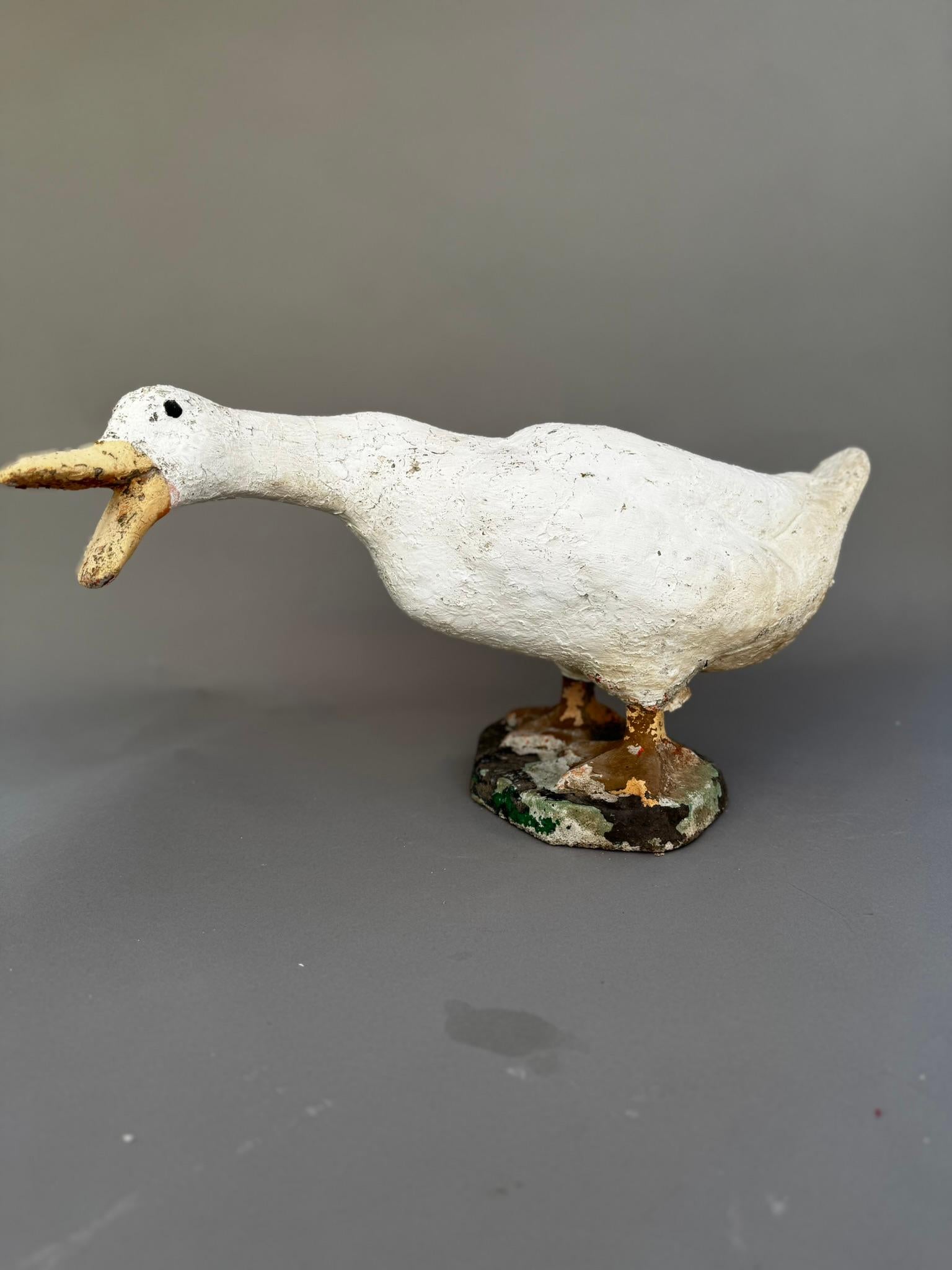 Aggiungi un tocco di estro e carattere vintage alla tua casa o al tuo giardino con questa scultura d'oca in cemento, progettata come fermaporta funzionale. Questo affascinante pezzo di metà secolo raffigura un'oca catturata a metà - con il becco