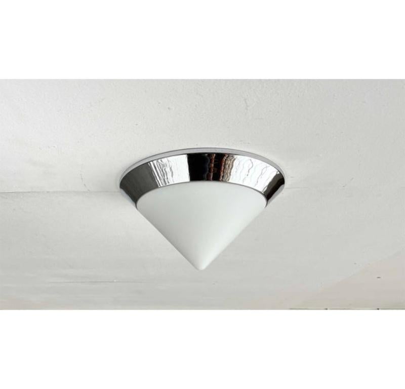 Cone-shaped glass ceiling light from the 80s.

A design in a postmodern design language. The conical diffuser is made of satin glass and framed by a chrome ring. The inclination of the ring blends harmoniously with that of the glass. The glass and