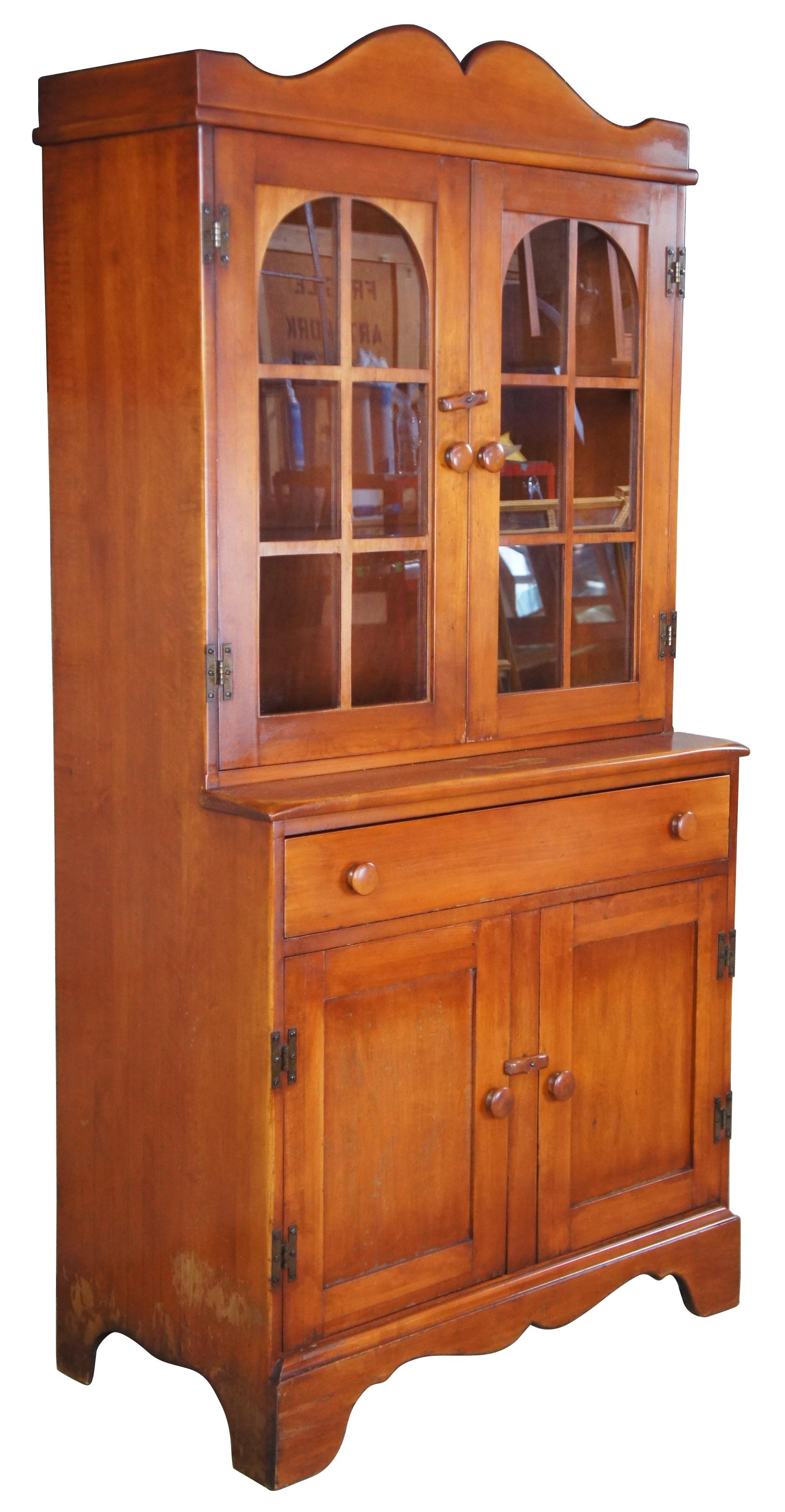Consider H. Willett No. 1967 China Hutch, Circa 1930s, as seen in their 1939 catalogue. An Early American Reproduction in Wild Cherry. Features 2 upper shelves behind paneled doors, a central drawer and lower cabinet for storage. Consider H wIllett