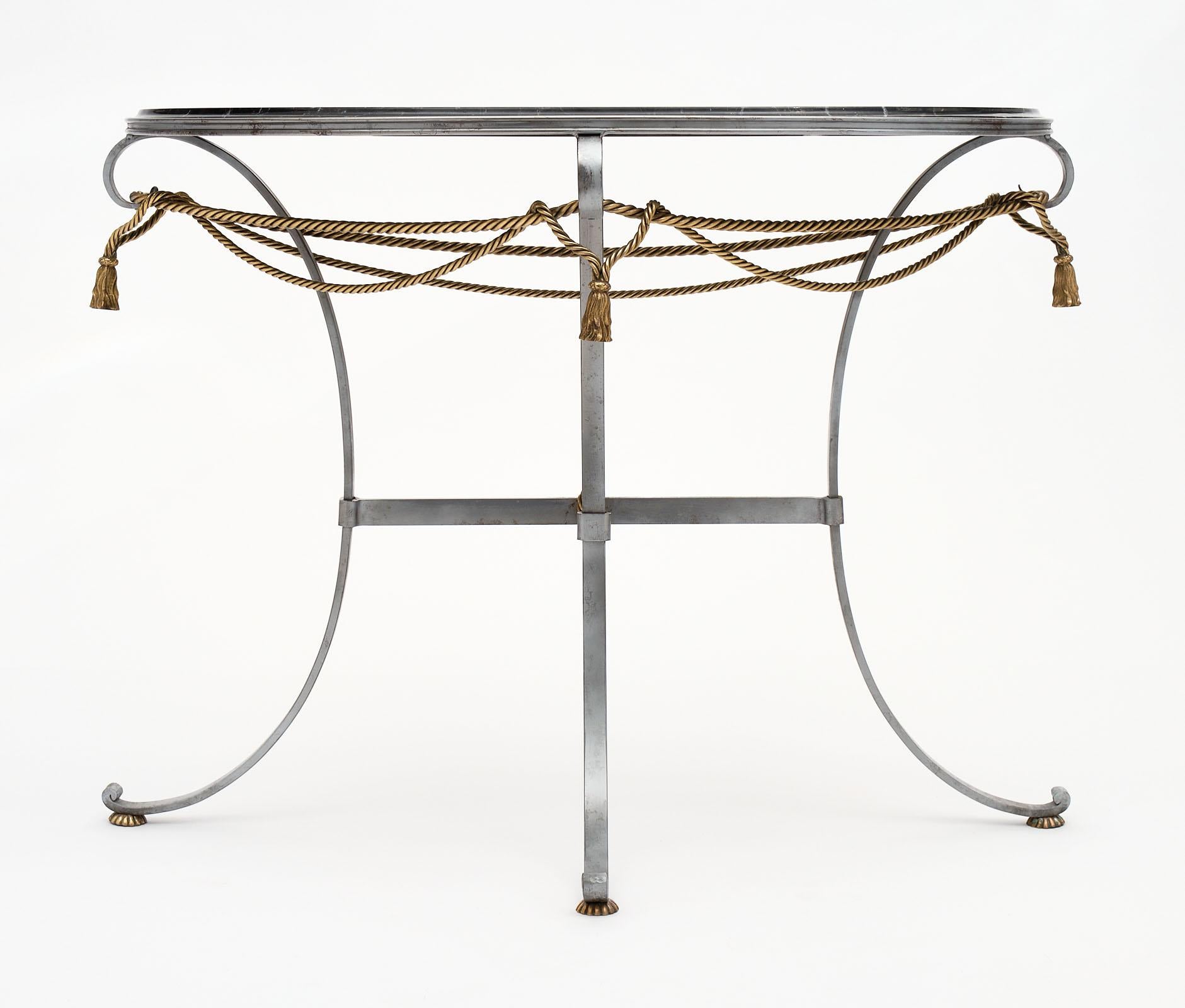 Vintage console table in a demilune shape with a black marble top. The base is made of steel with brass stylized decor of interlaced ropes. The top is black marble with beautiful veining throughout.