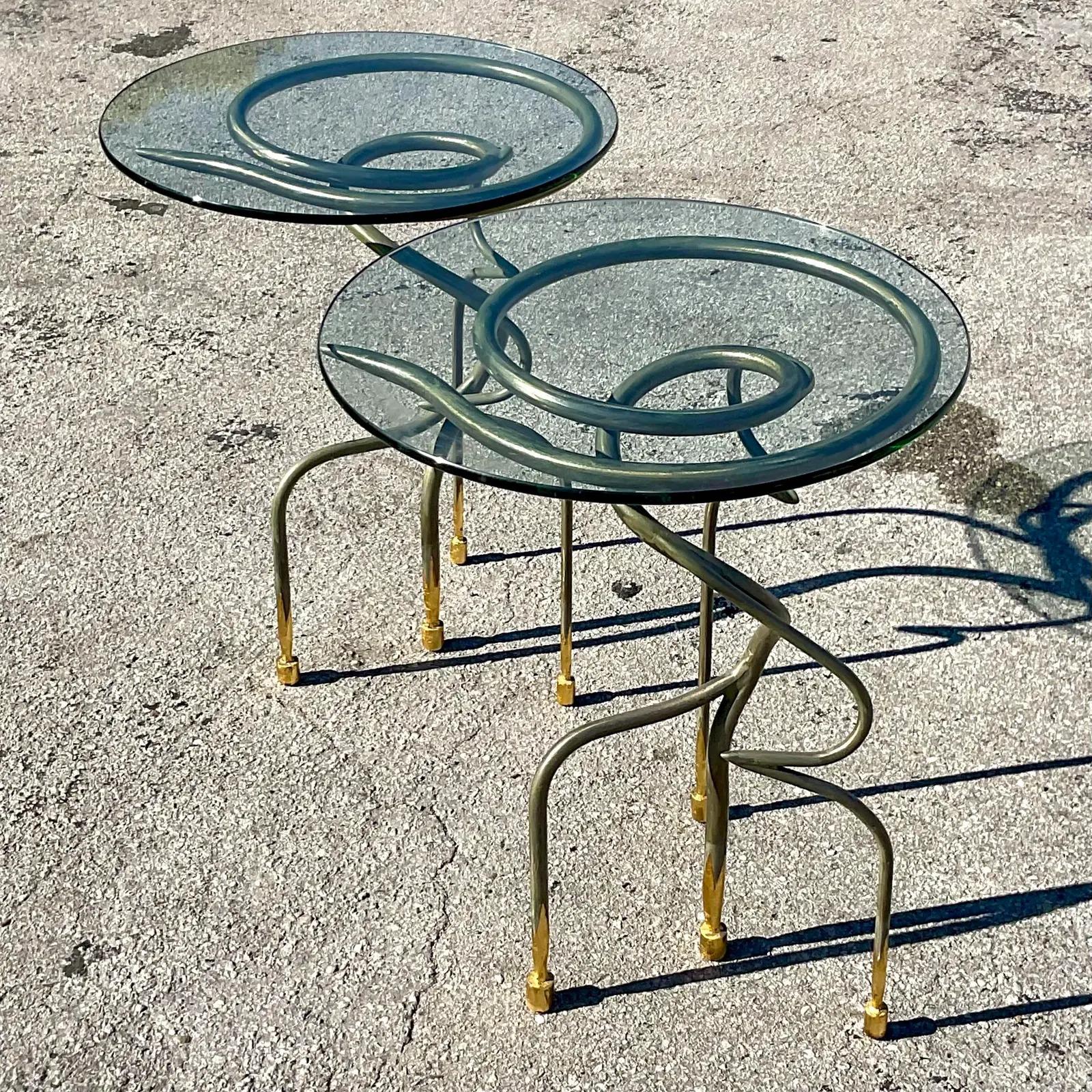 A fabulous pair of vintage Contemporary side tables. a chic abstract swirl design in steel. The legs are tipped in gold leaf. Acquired from a Palm Beach estate.
