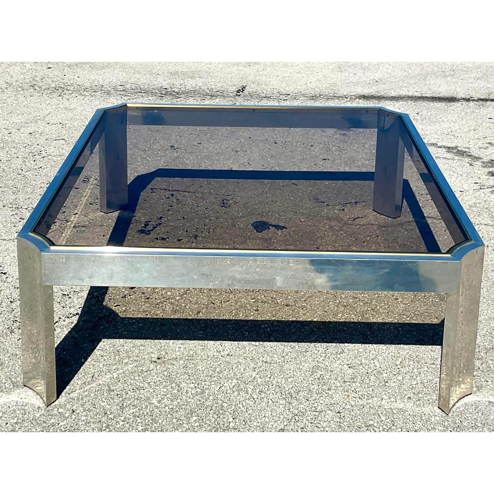 Fabulous vintage Contemporary coffee table. Chic notched corners with brushed chrome and brass inlay. Inset smoked glass center panel. Acquired from an El Cid estate.