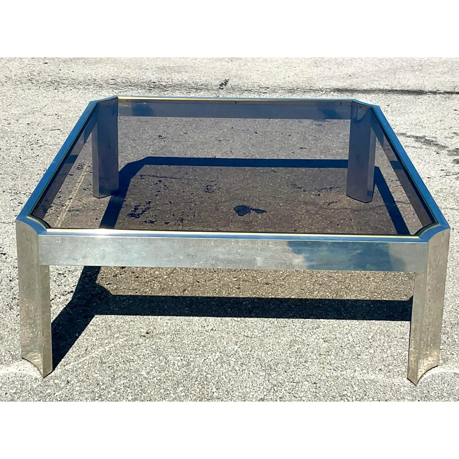 Fabuleuse table basse vintage contemporaine. Coins crantés chic avec incrustation en chrome et laiton brossés. Panneau central en verre fumé. Acquis d'une propriété d'El Cid.