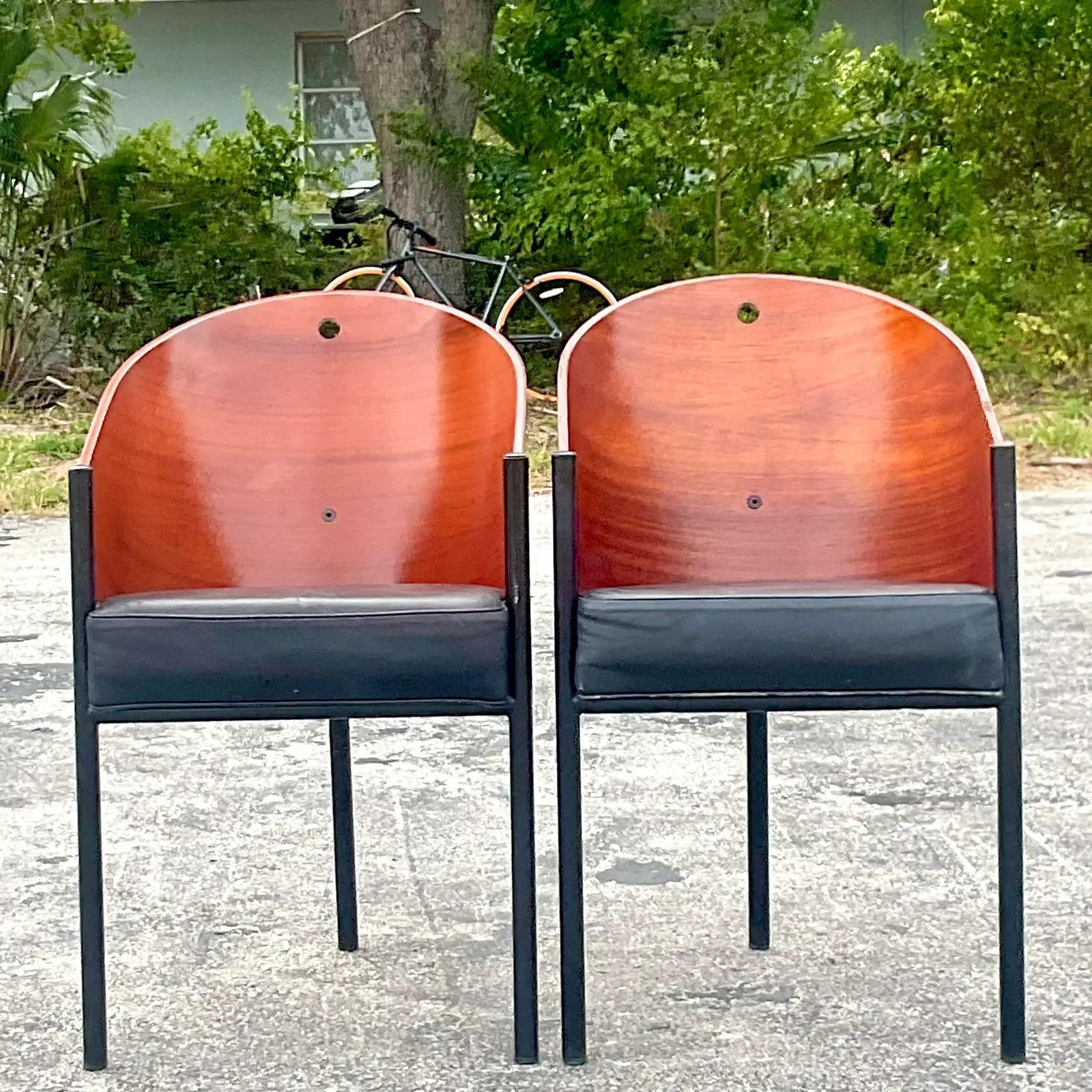 A fabulous pair of vintage Contemporary dining chairs. Chic Mahogany and leather in the iconic shape designed by Phillipe Starck. Immediate adds a flash of glamour to any space. Acquired from a Palm Beach estate. 