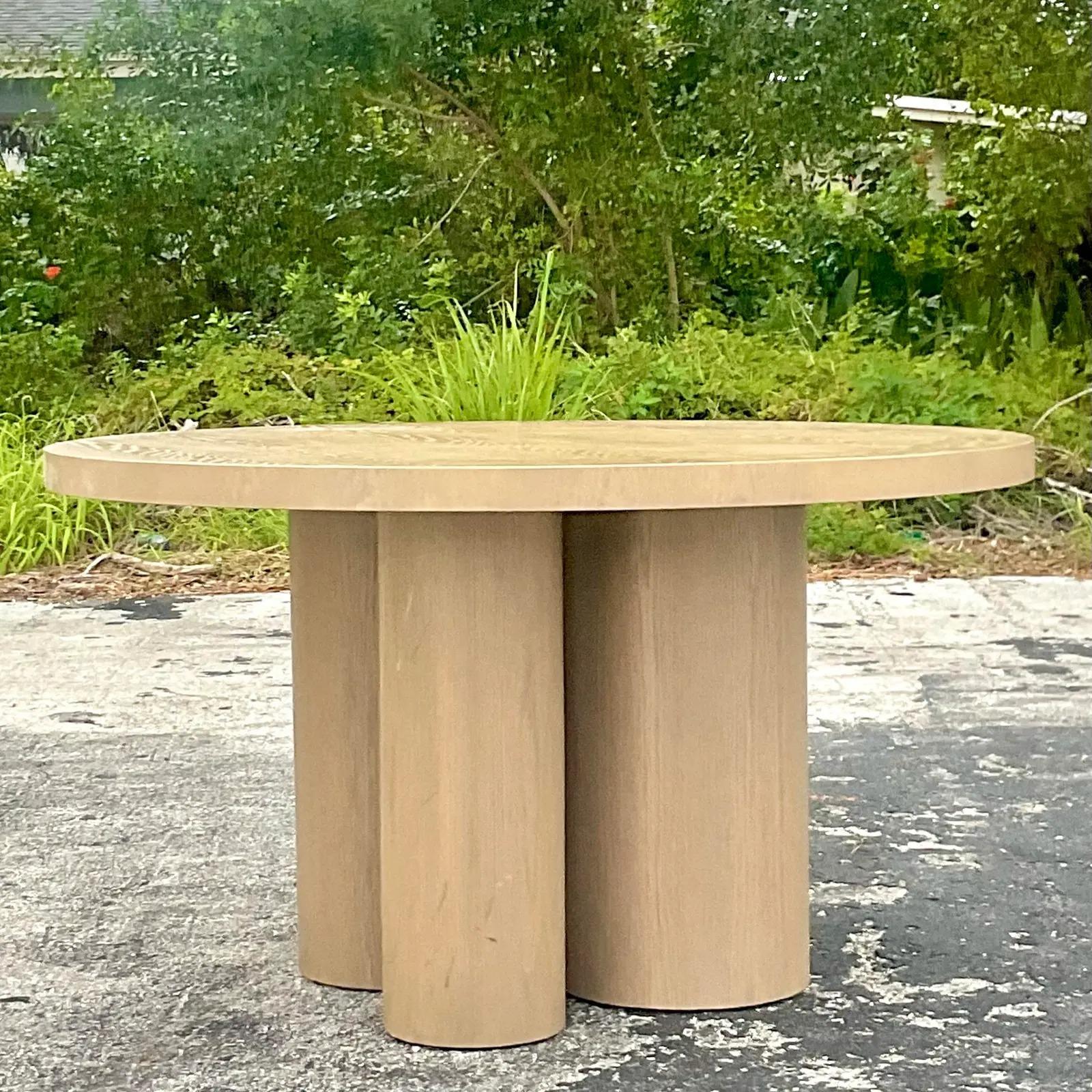 A fabulous vintage Contemporary dining table. A super chic cerused custom built wood round table. Rests on a trio of multi sized cylinder clustered pedestals. Acquired from a Palm Beach estate.