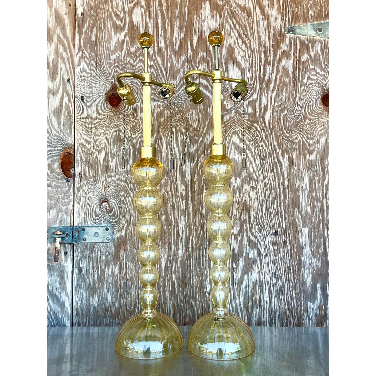 Fantastic vintage pair of Murano glass lamps. The iconic glass ball bearing shape. Beautiful striped glass that is signed on the base. Twisted raw silk cord. Acquired from a Palm Beach estate.

The lamps are in great vintage condition. Minor