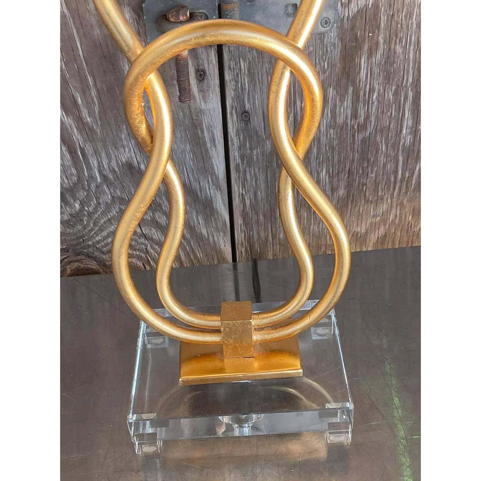 A fantastic pair of vintage Contemporary table lamps. Beautiful linked gilt rings resting on a lucite plinth. Coordinating shade in an ecru color. Acquired from a Palm Beach estate. 

The lamps are in great vintage condition. Minor scuffs and