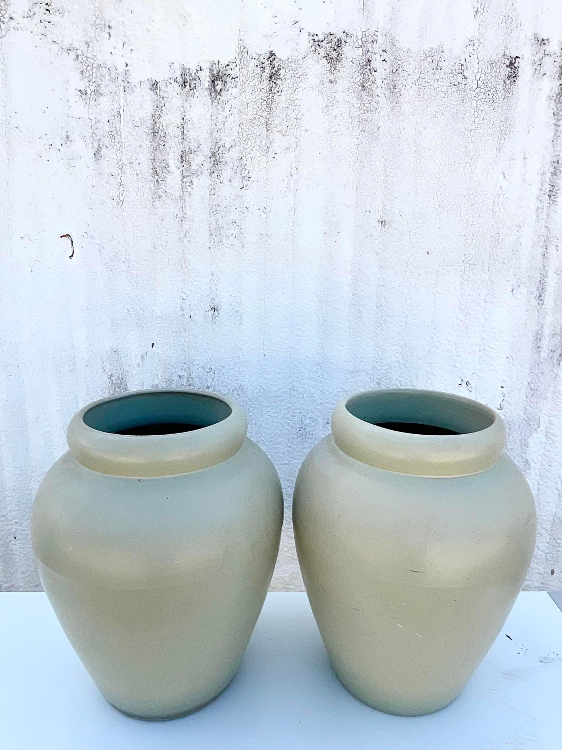 Vintage Contemporary pair of urns. Beautiful matte glazed finish in a pale green color. Drilled for draining. Part of a collection of urns that are also available on my Chairish page. Acquired from a Palm Beach estate. 