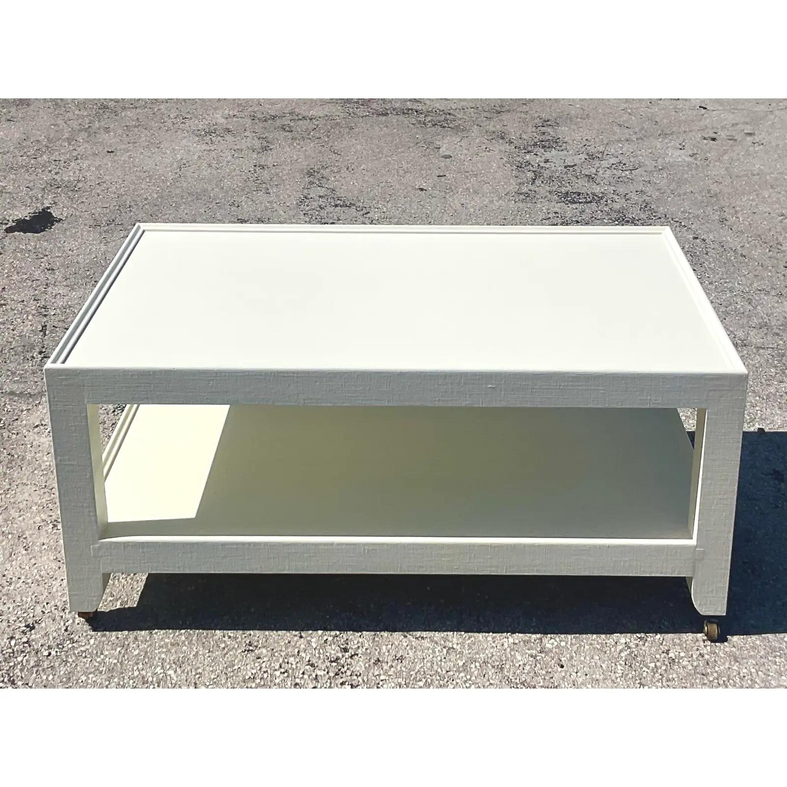 A stunning vintage Contemporary coffee table. Made by the iconic Karl Springer and tagged on the bottom. A chic and simple design with a linen wrapped surface. A Parzinger white finish. Acquired from a Palm Beach estate.