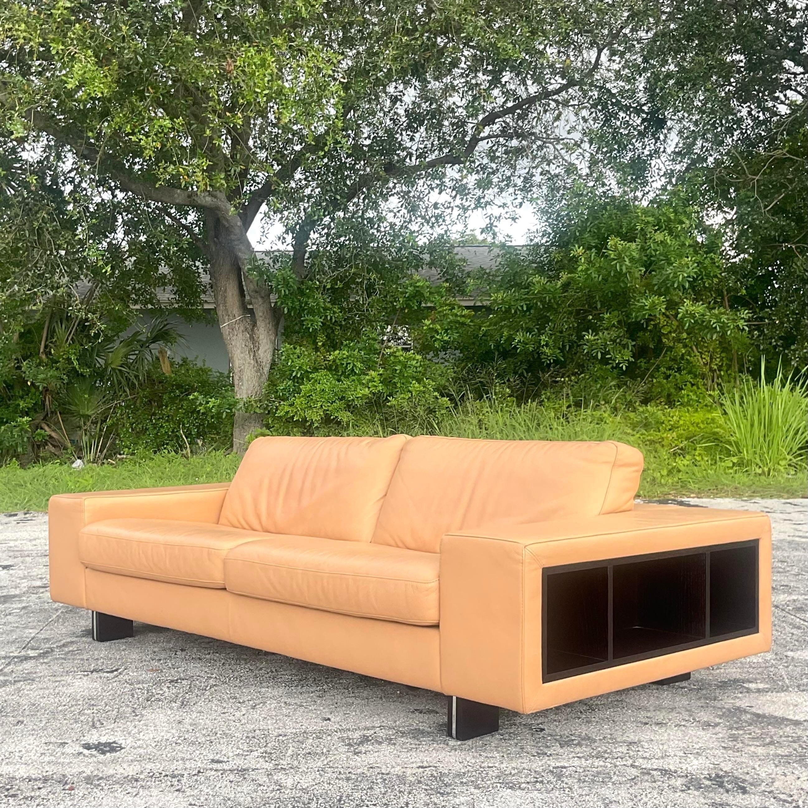 An exceptional vintage Boho leather sofa. Made by the iconic Roche Bobois group and tagged below the seat. A chic low profile in leather with ebony blade legs. Wrap around open cabinets for display. Acquired from a Palm Beach estate