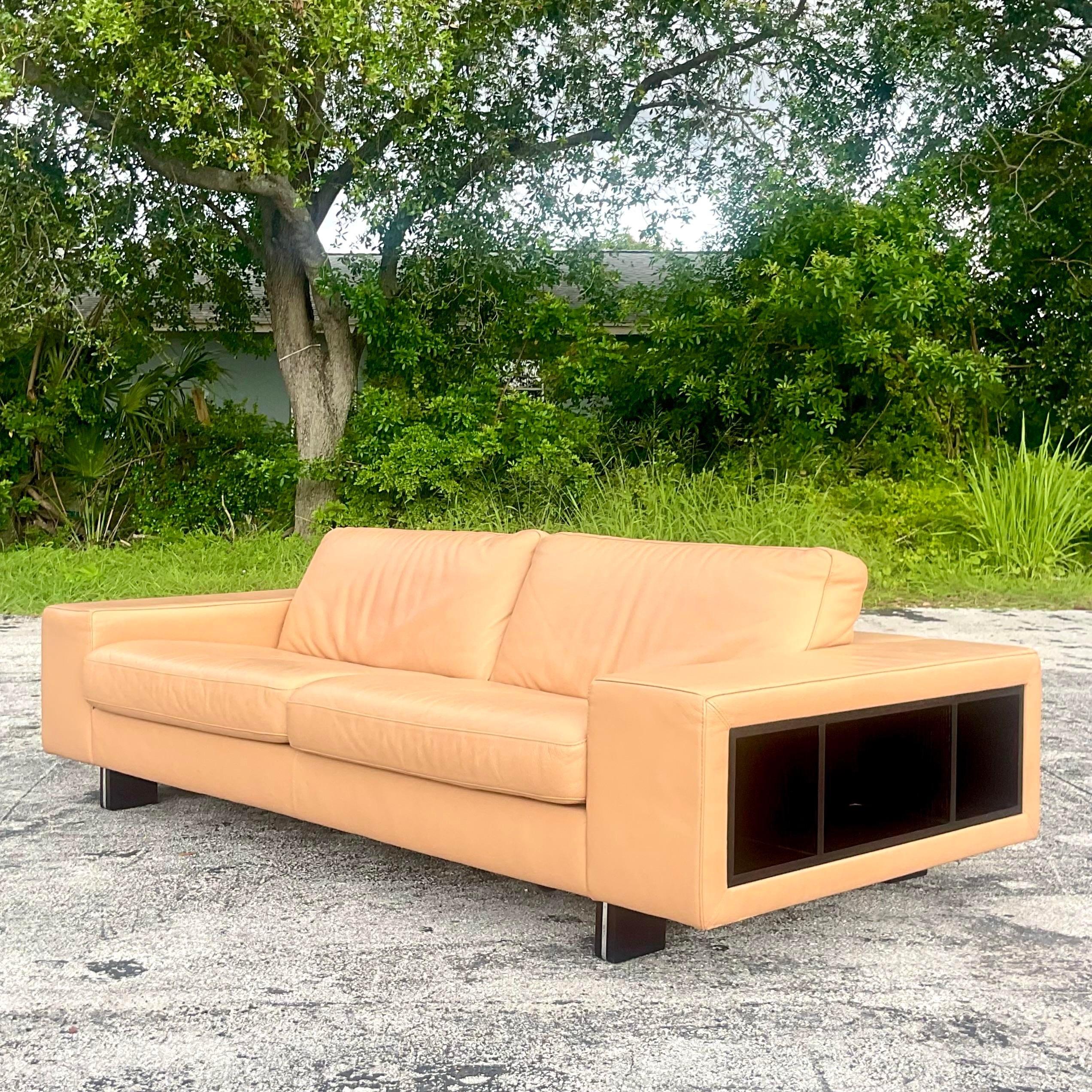 An exceptional vintage Boho leather sofa. Made by the iconic Roche Bobois group and tagged below the seat. A chic low profile in leather with ebony blade legs. Wrap around open cabinets for display. Acquired from a Palm Beach estate.