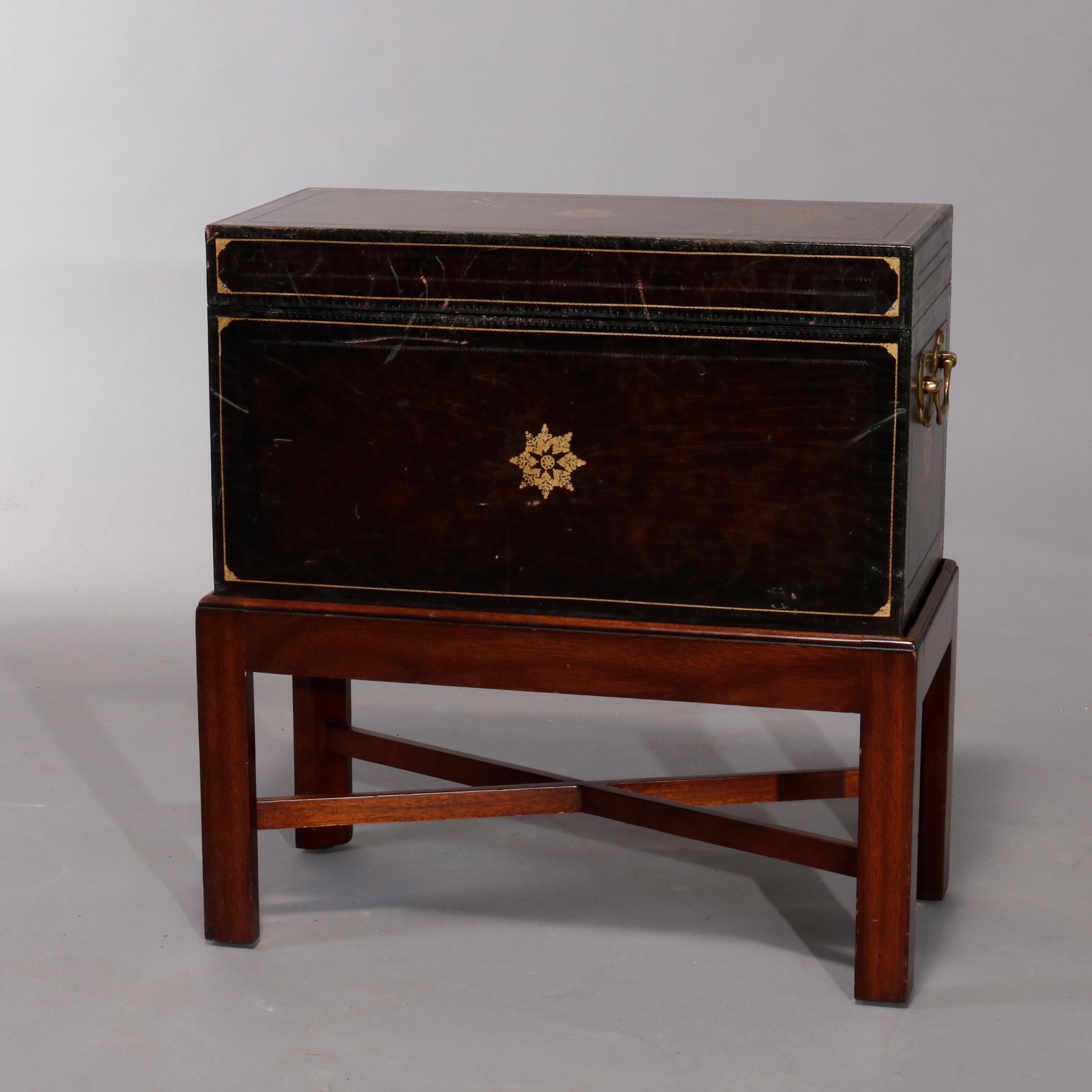 A vintage Continental dowry or document box offers leather covering with gilt banding with central stylized stars, cast brass handles, and covered interior, seated on mahogany stand with straight legs and cross stretcher, 20th century.

Measures: