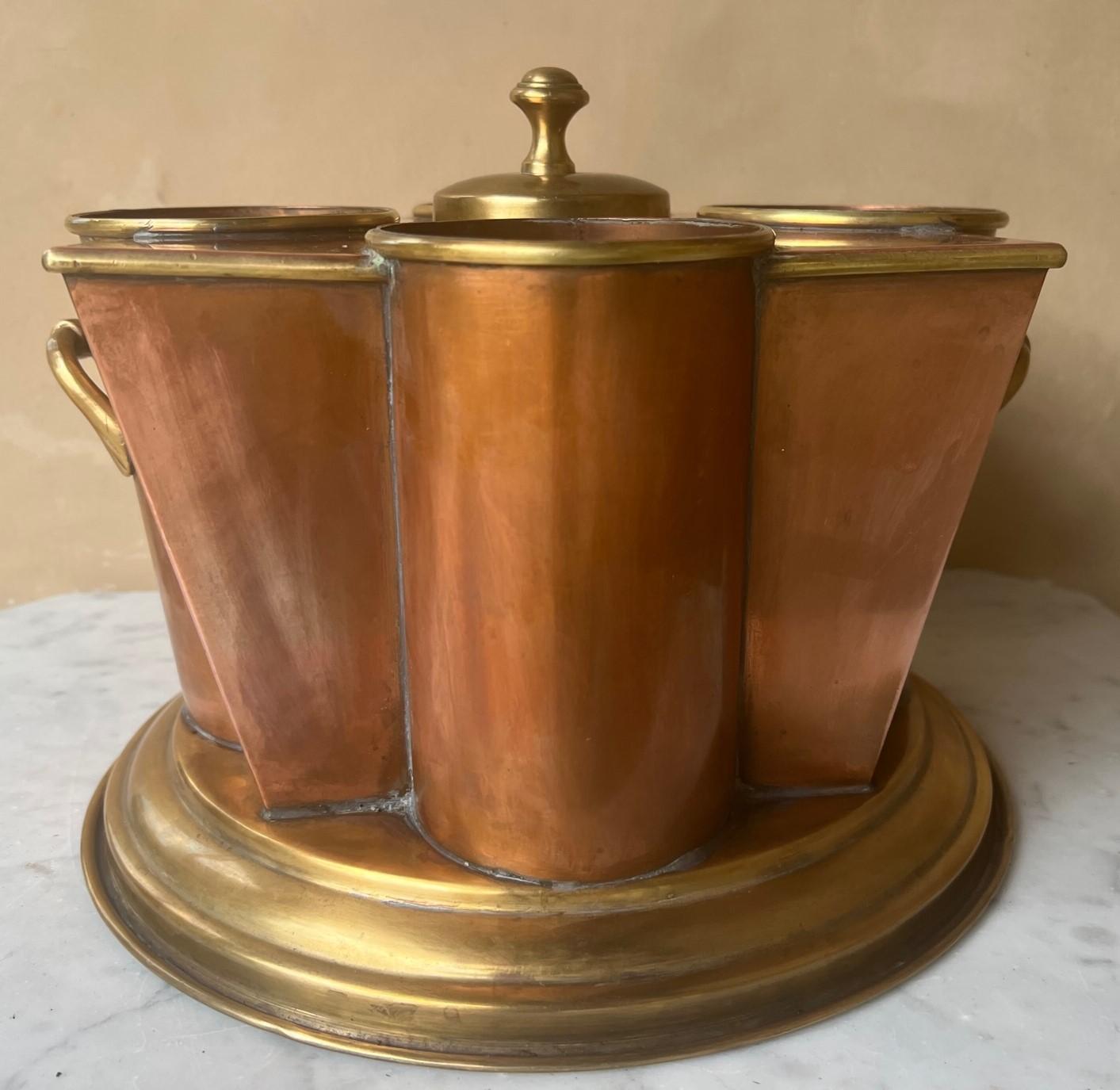 Art Deco style copper & brass wine cooler with 4 areas for individual bottles centering a covered opening to hold ice.