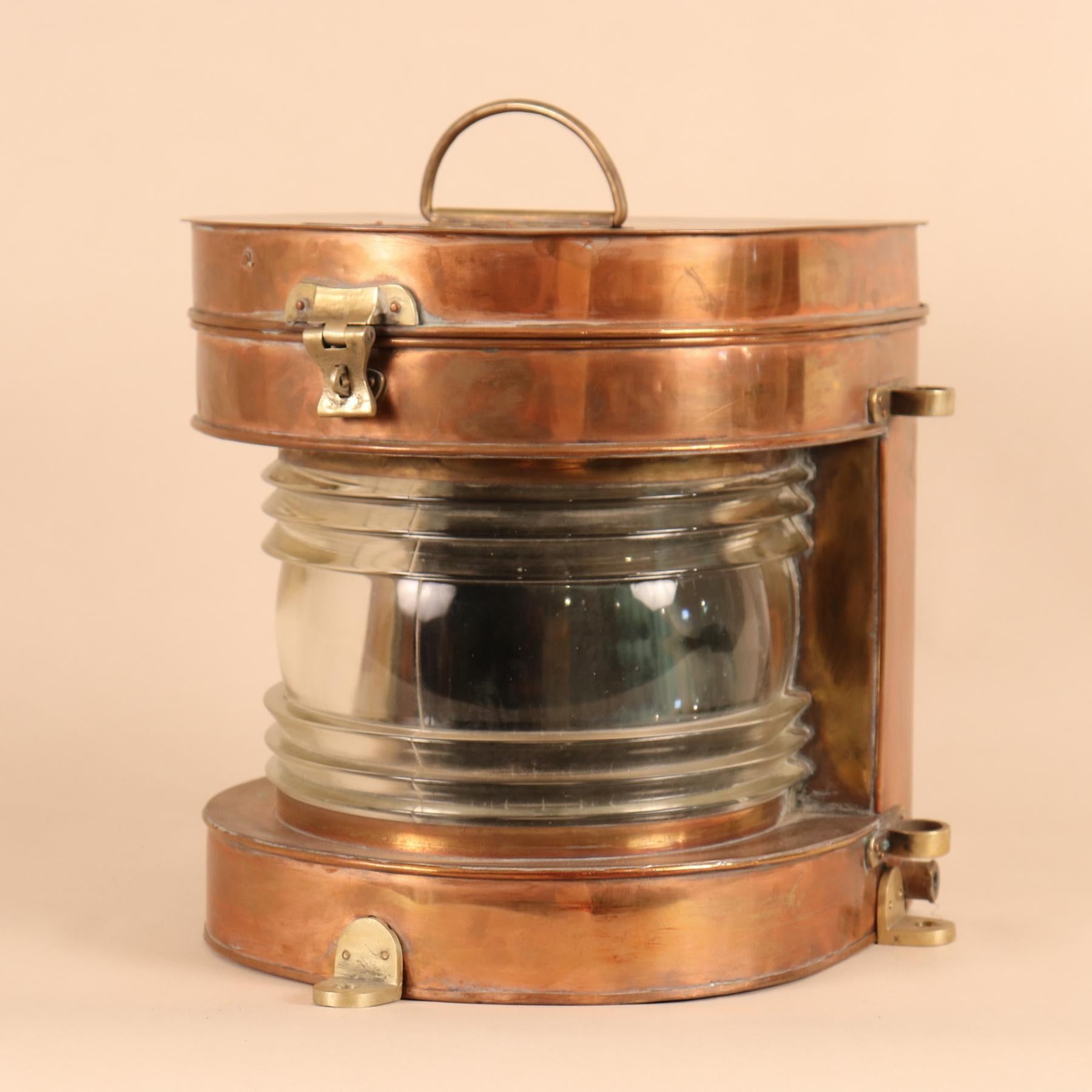 An authentic, vintage copper nautical lantern with brass accents and thick glass Fresnel lens. This circa 1950 marine light, manufactured by Tung Woo, Hong Kong, is hinged and hasped on top so that changing the bulb is easy. The lantern has all of
