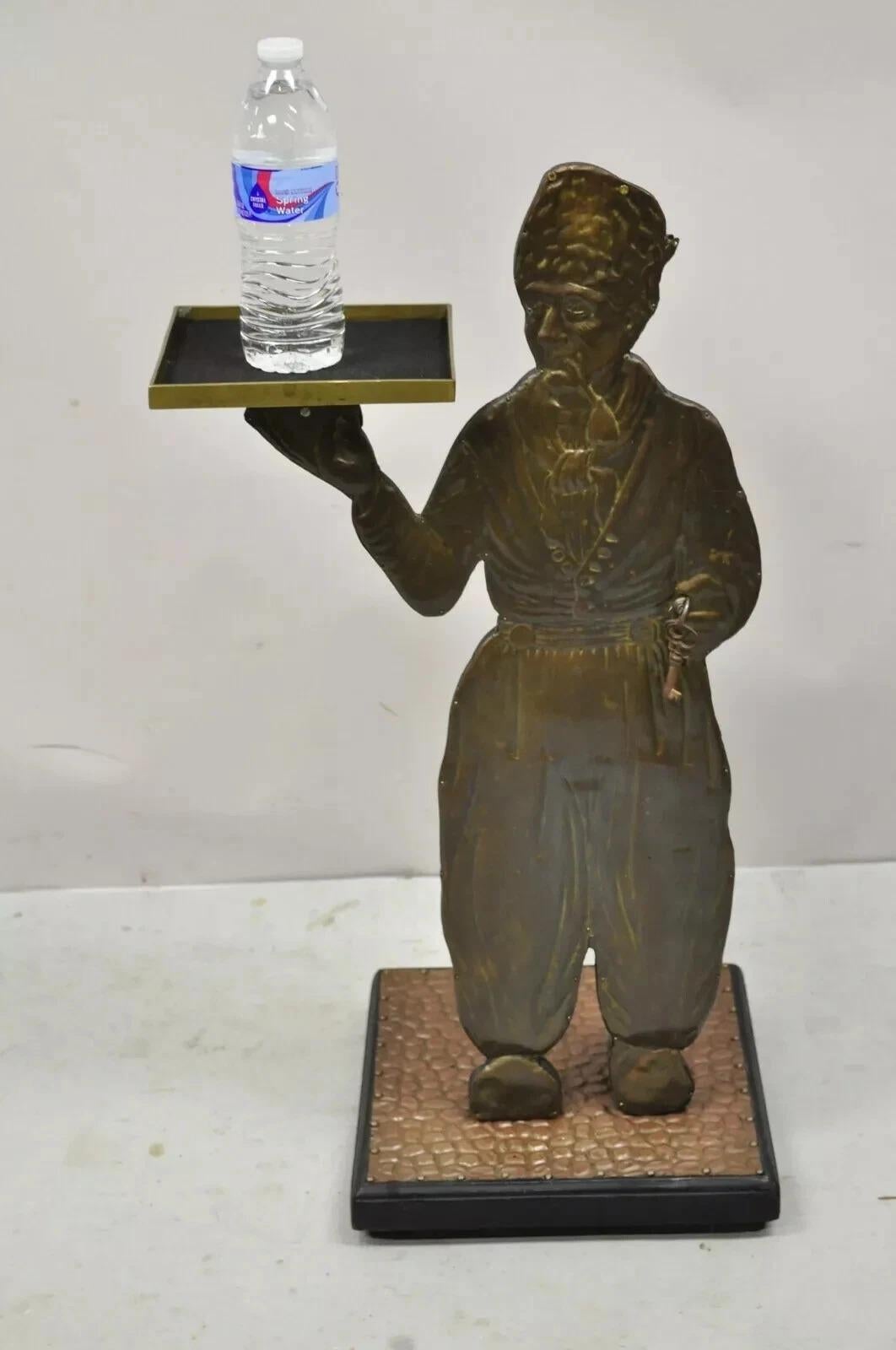 Figura di uomo olandese in rame dell'ingresso, portachiavi e portacatino. L'articolo presenta una figura in rame sbalzato di un uomo olandese in piedi su un terreno di ghiaia che tiene in mano un vassoio, un piccolo portachiavi nella mano sinistra,
