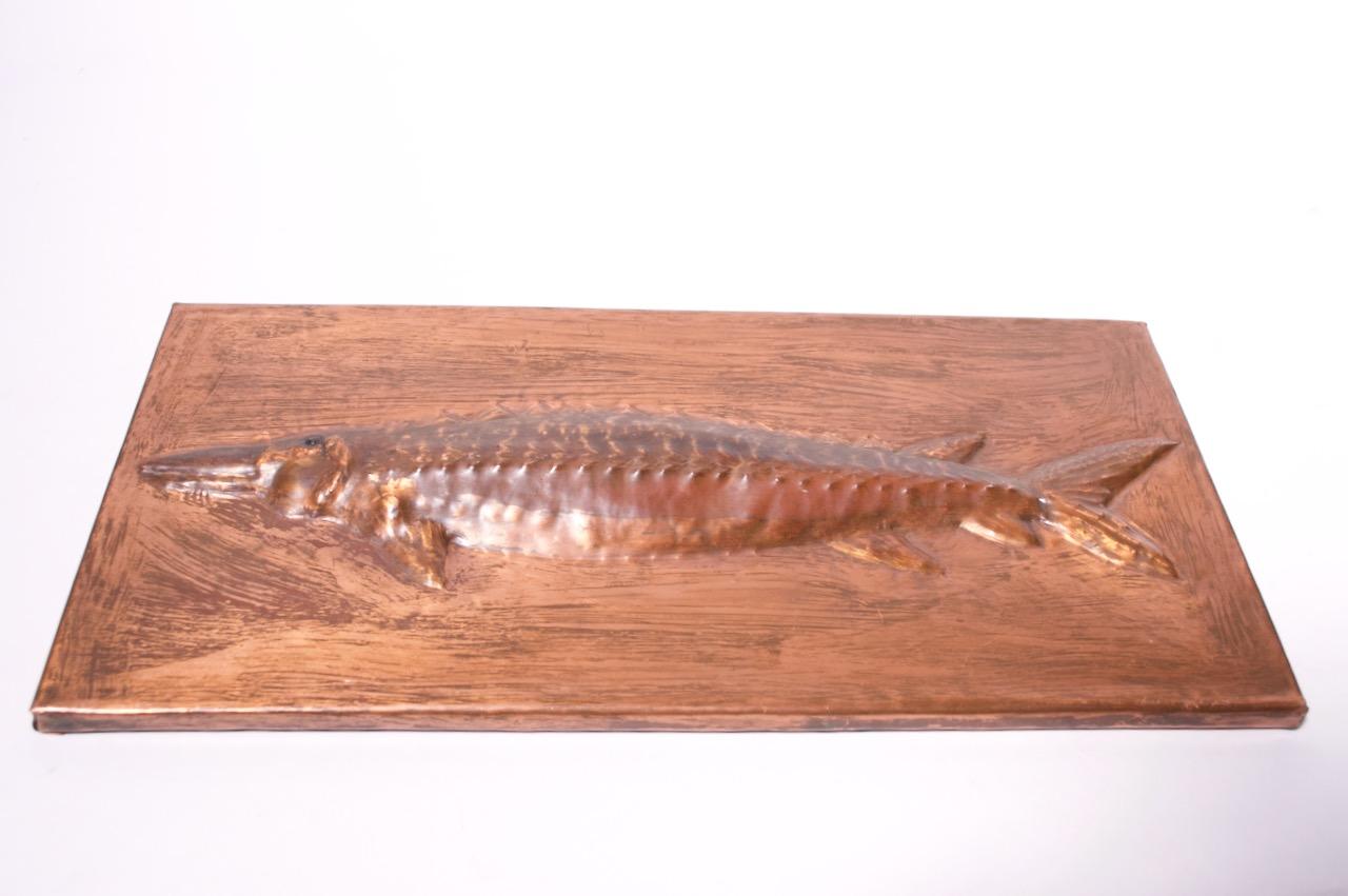 Plaque de poisson unique (probablement un barracuda ou un autre poisson à nageoires rayonnées) en cuivre. Présence d'un support pour le montage mural. 
Très bon état vintage. 
Mesures : H 6,5