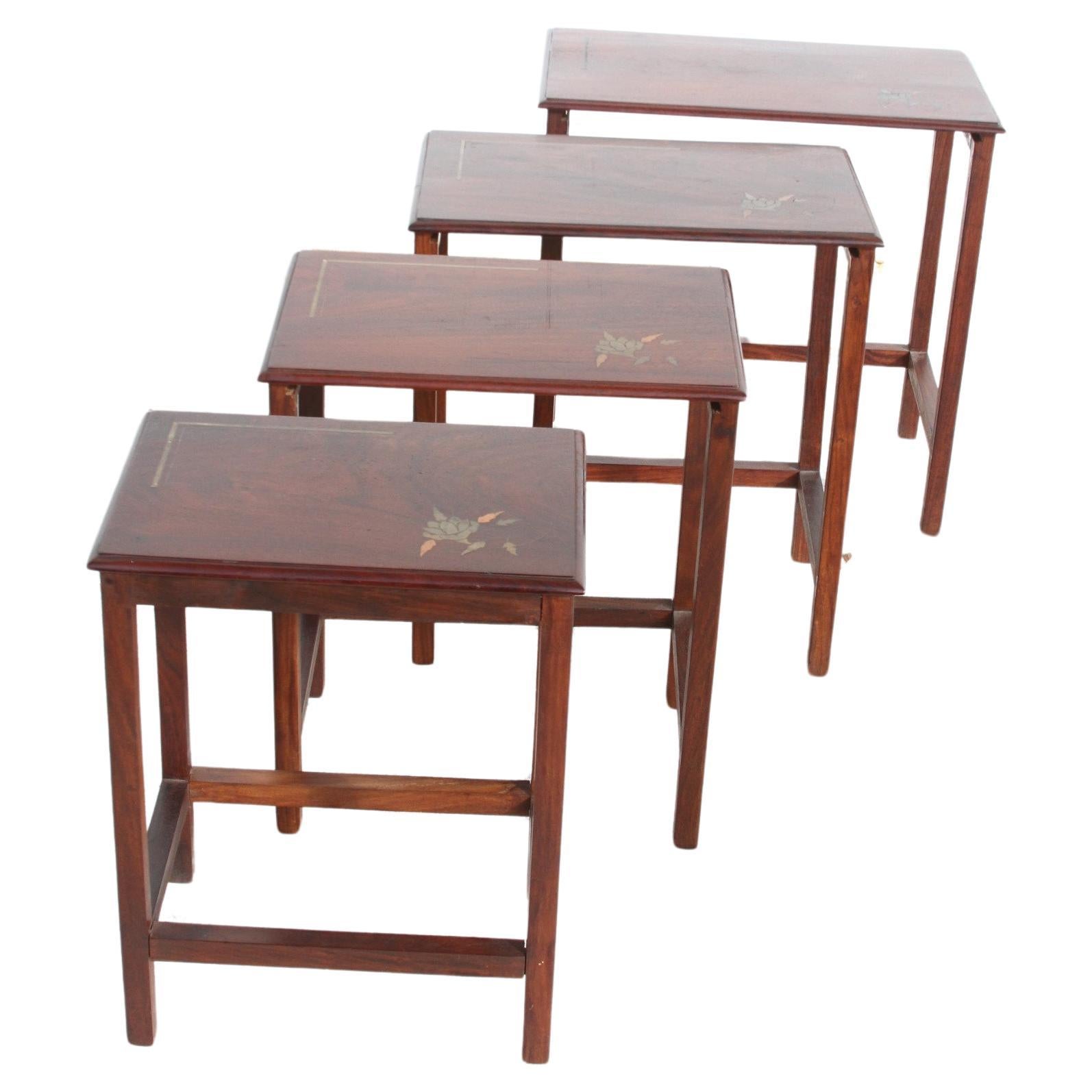This is a set of nesting tables with copper inlaid tops. There are 4 tables in this set that graduate in size. They stack together to make a single table or 4. The flower inlay and banding are very well rendered. Flower, leaves and banding are done