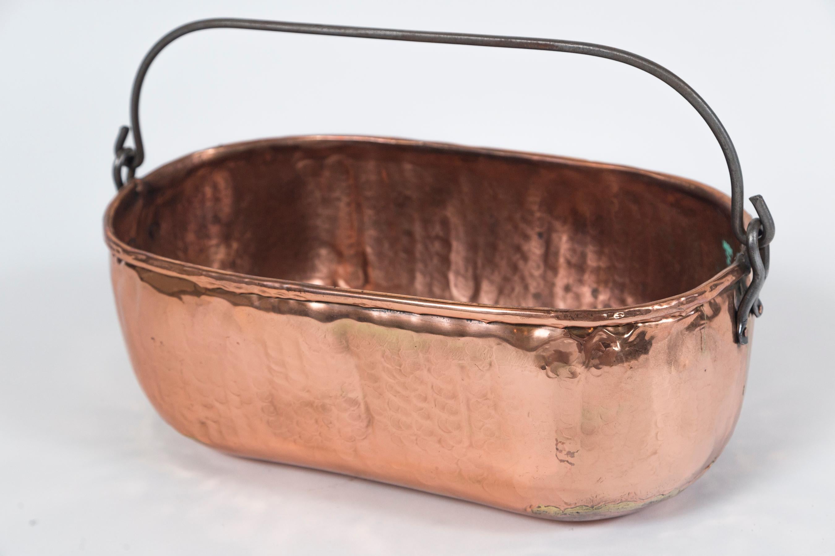Antique copper oval bucket, circa 1910. Dovetailed sides and bottom, with rolled rim. Iron swing handle.