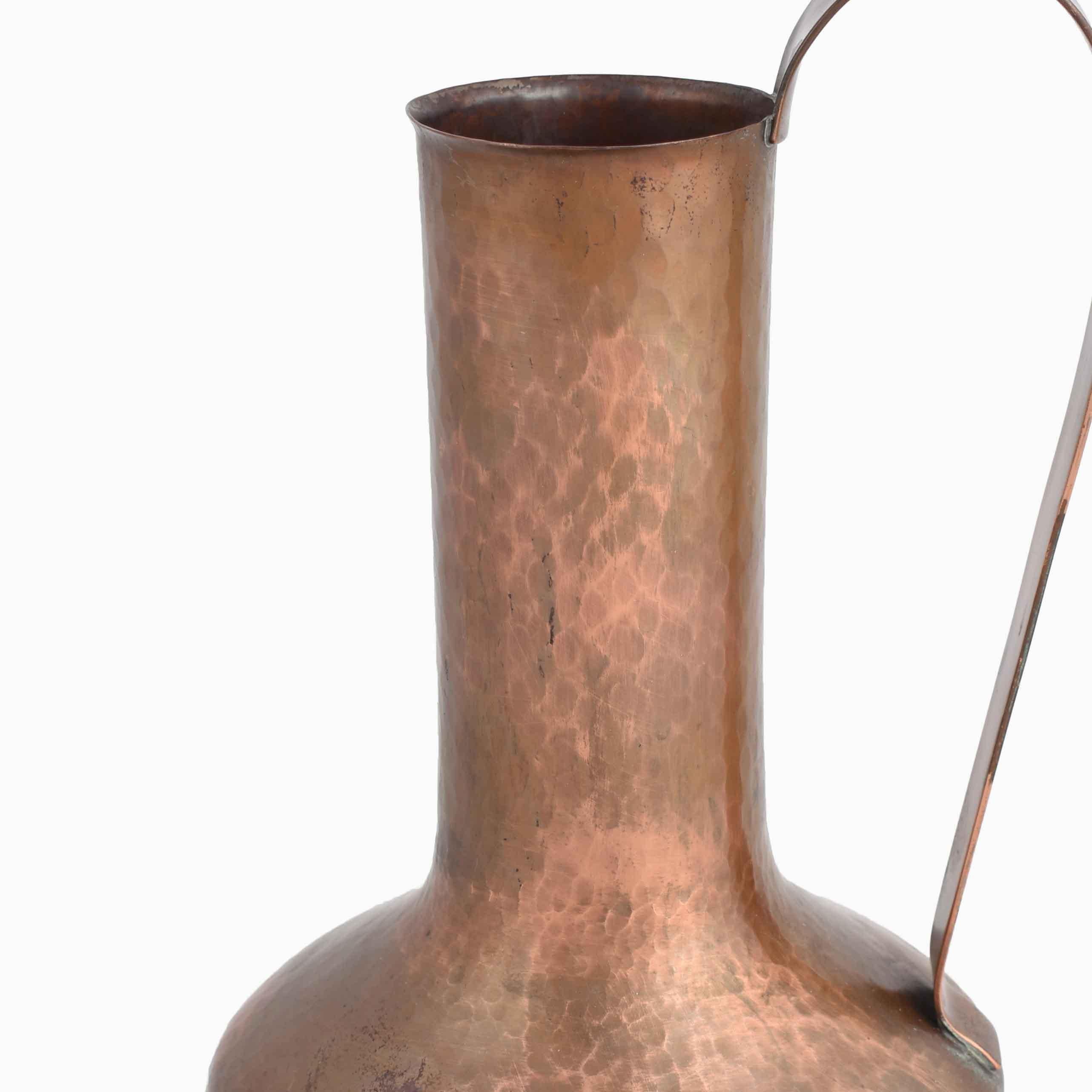 Copper vase with handle is an original decorative object realized in the mid-20 century.

Original copper artwork. 

Good conditions: vintage signs of use. 

The work is a very beautiful metal with a pressed body and a long cylindrical neck.