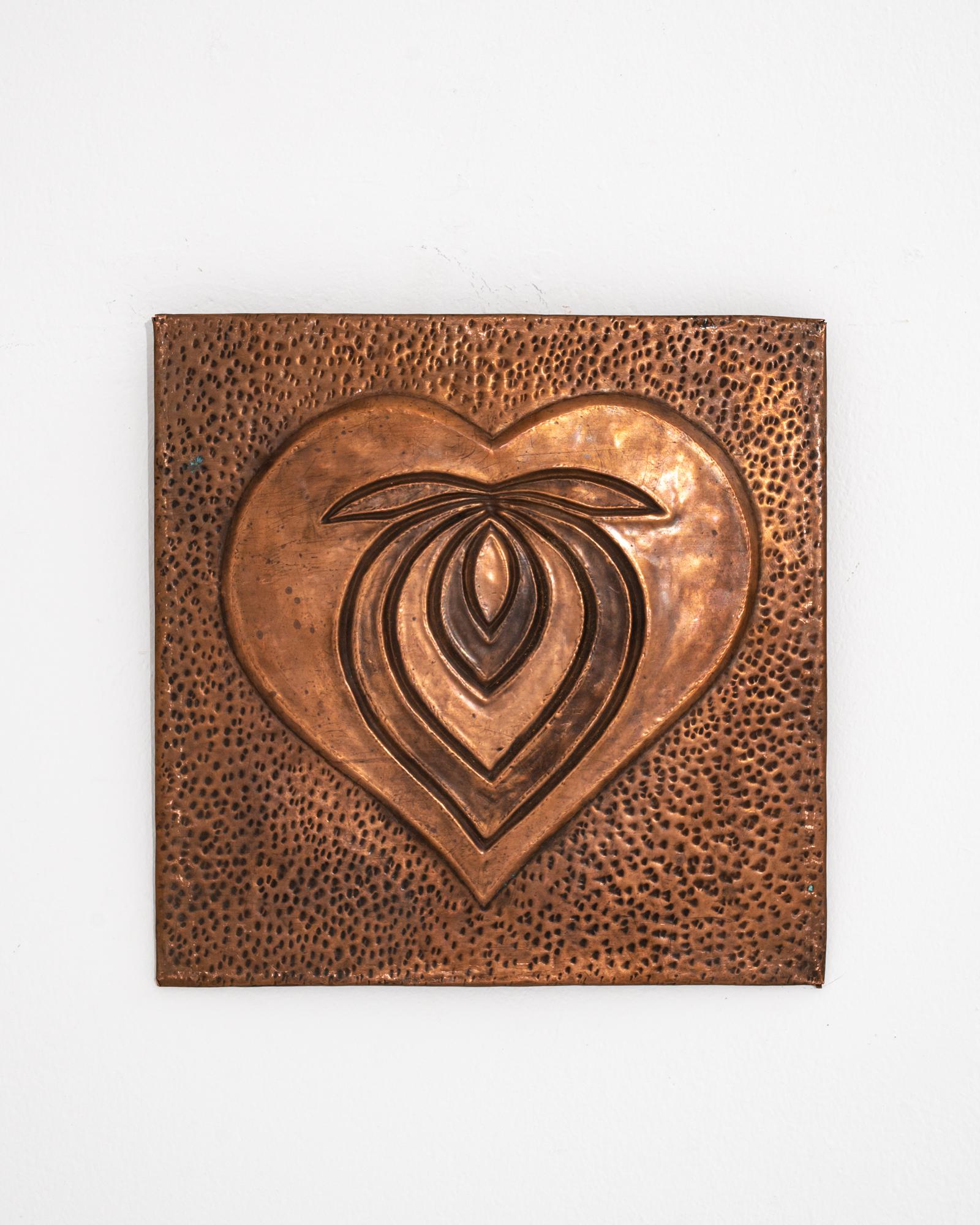 Graphic and eye-catching, this copper wall decoration makes a unique vintage accent. The square plaque is decorated with a raised metal symbol —abstract and typographic, the form resembles a stylized heart. The background is composed of marks made