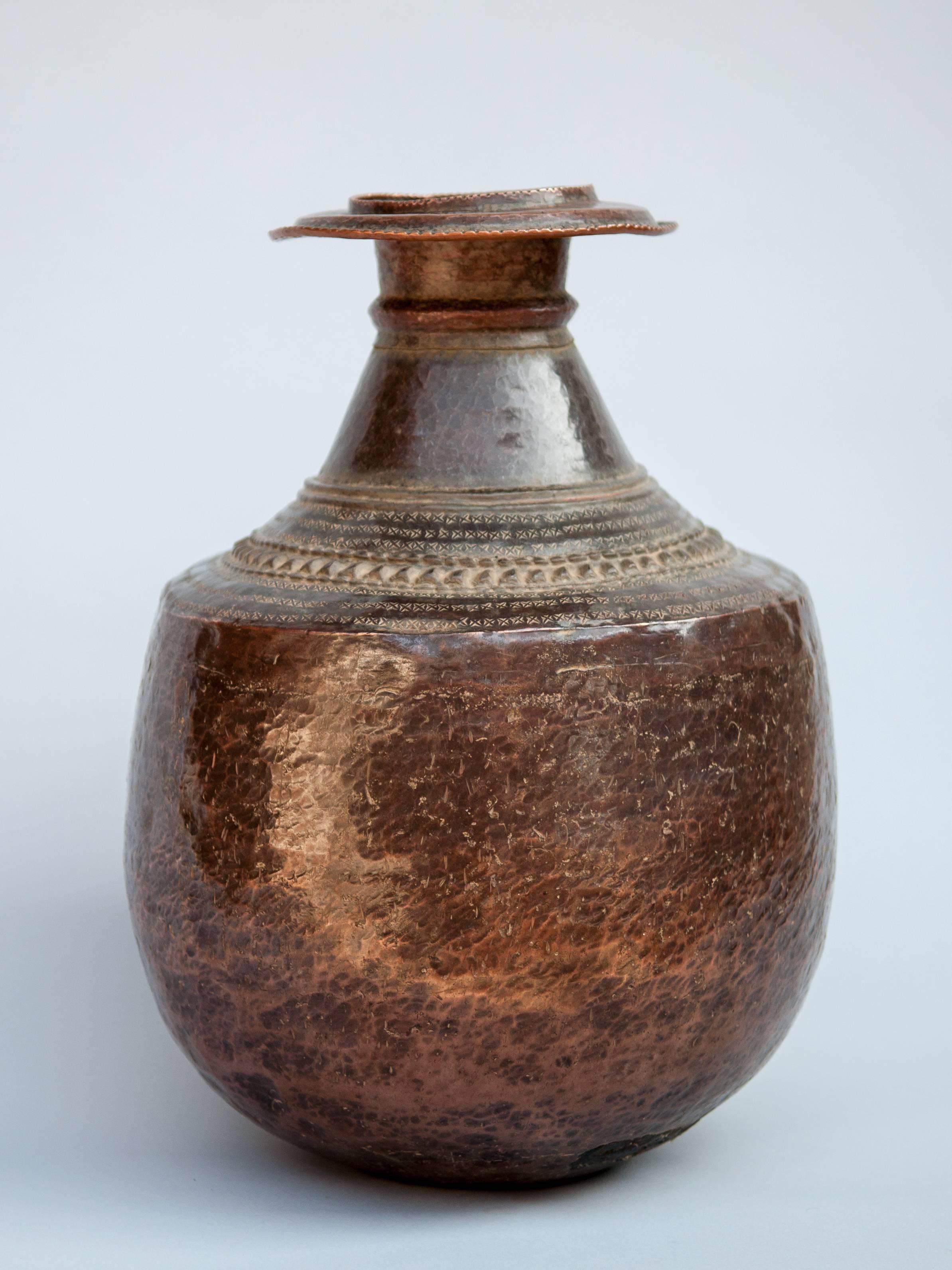 Vintage copper water pot from Nepal, mid-20th century.
A beautifully balanced pot with an aged patina, and hand-hammered decorative repousse work around the shoulder, it was used to collect water and carry back to the home. In Nepal these pots are