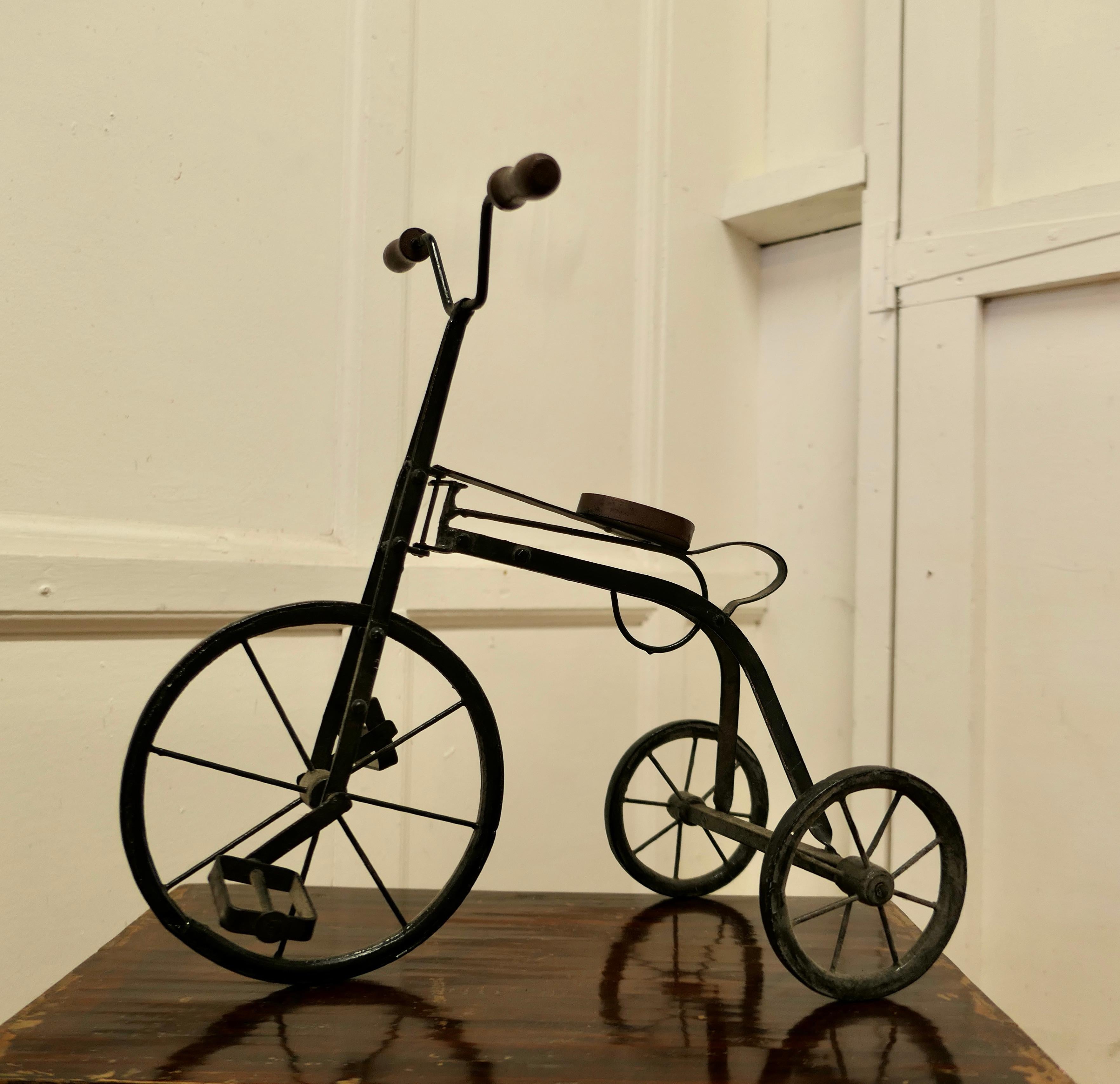 Vintage copy of a 19th century pedal tricycle 

A delightful piece, this is a hand made copy, made some 60 years ago of a well known 19th century design, surely an antique of the future
The frame and wheels are made in iron, and the seat is