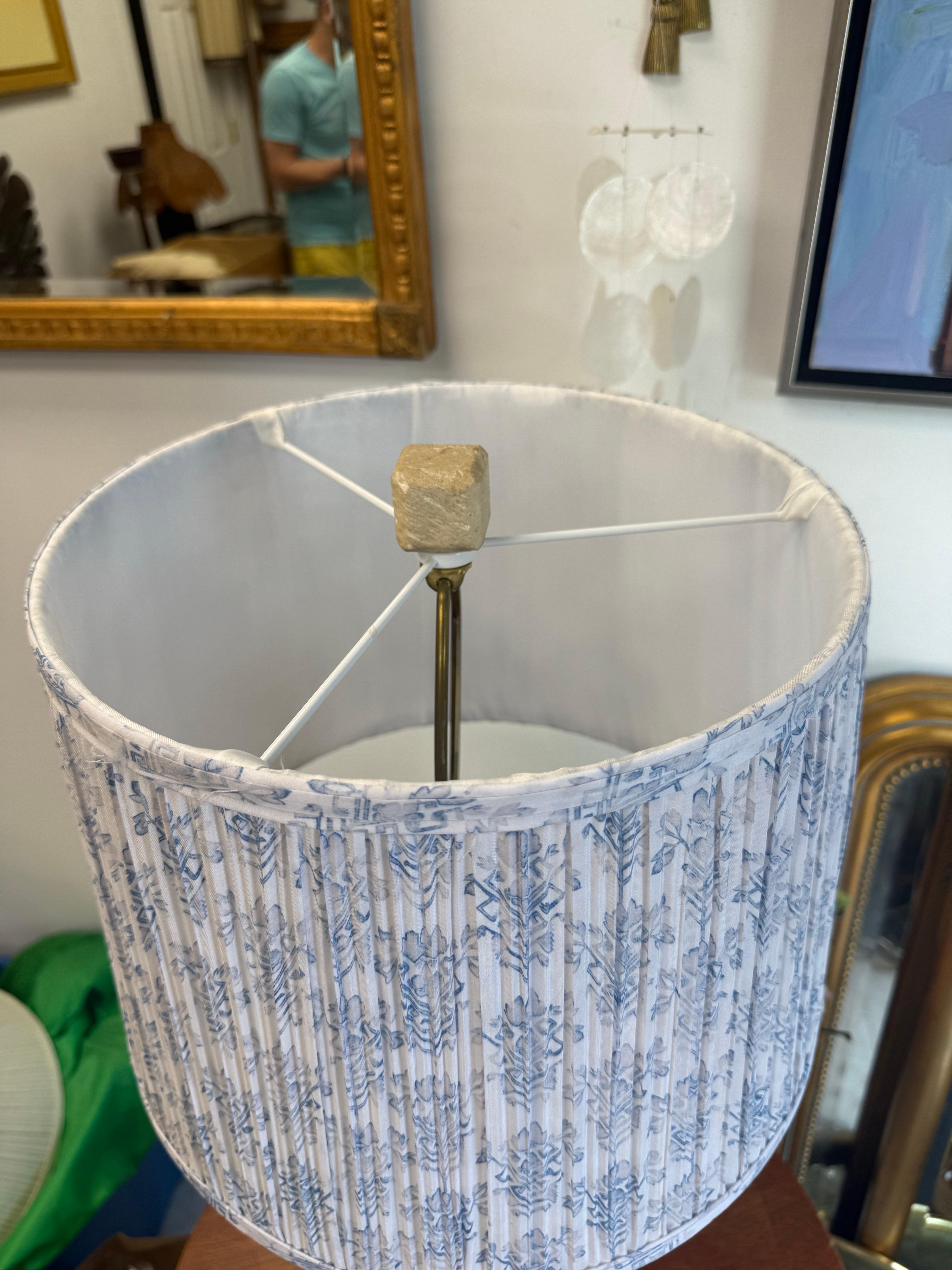 A solid piece of coquina coral stone in cylinder form.   The details of this piece are amazing.  Paired with a pleated floral blue and white shade.   
Lamp with harp, shade and finial measures : 29.5”’tall x 14” diameter