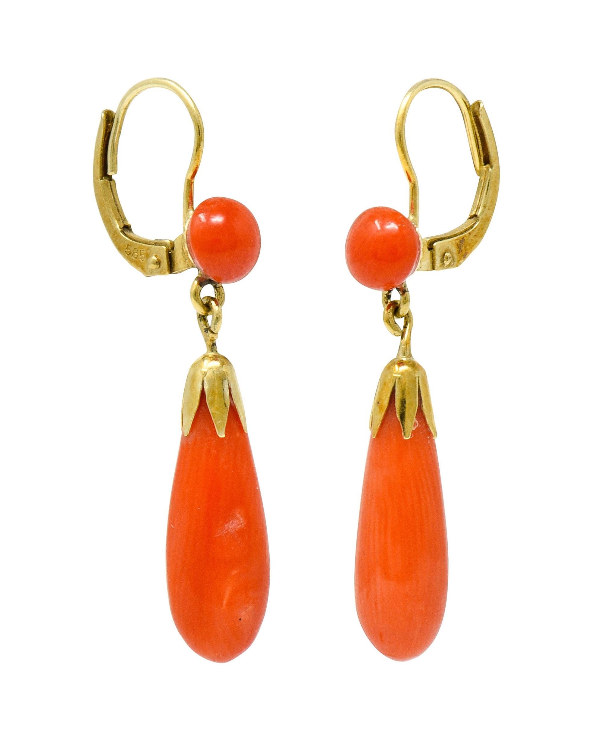 Drop earrings are designed with 5.5 mm round coral button cabochon surmounts

Suspending articulated pampel coral drops with a scalloped gold cap

Coral is opaque and a well-matched reddish-orange color

Completed by hinged leverbacks

Stamped 585