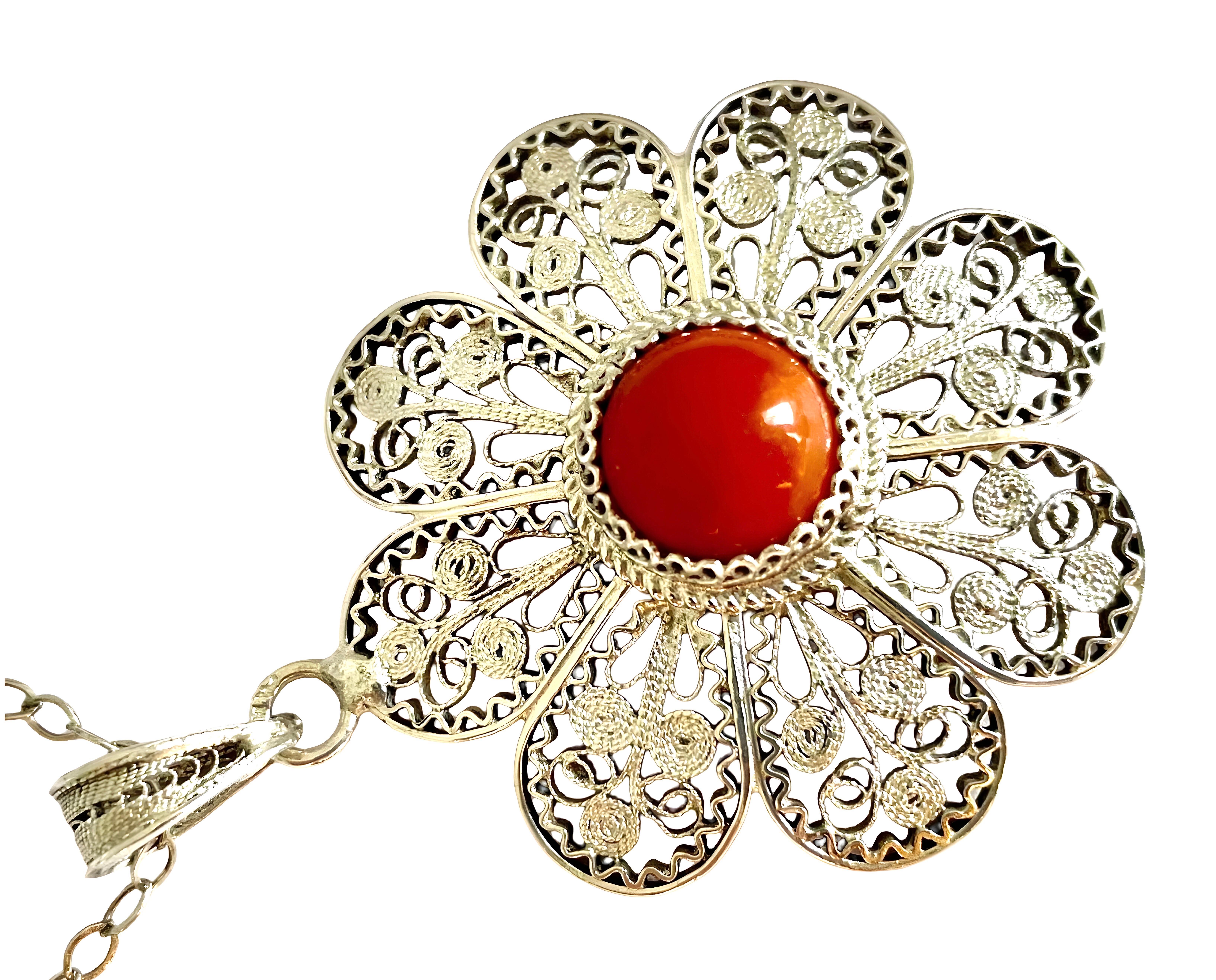 Ciondolo e catena in argento 925 con filigrana di corallo di eccezionale bellezza. Il ciondolo ha un design a forma di fiore con delicate volute e perline in argento e la gemma di corallo è incastonata in un bordo decorato. La tecnica della