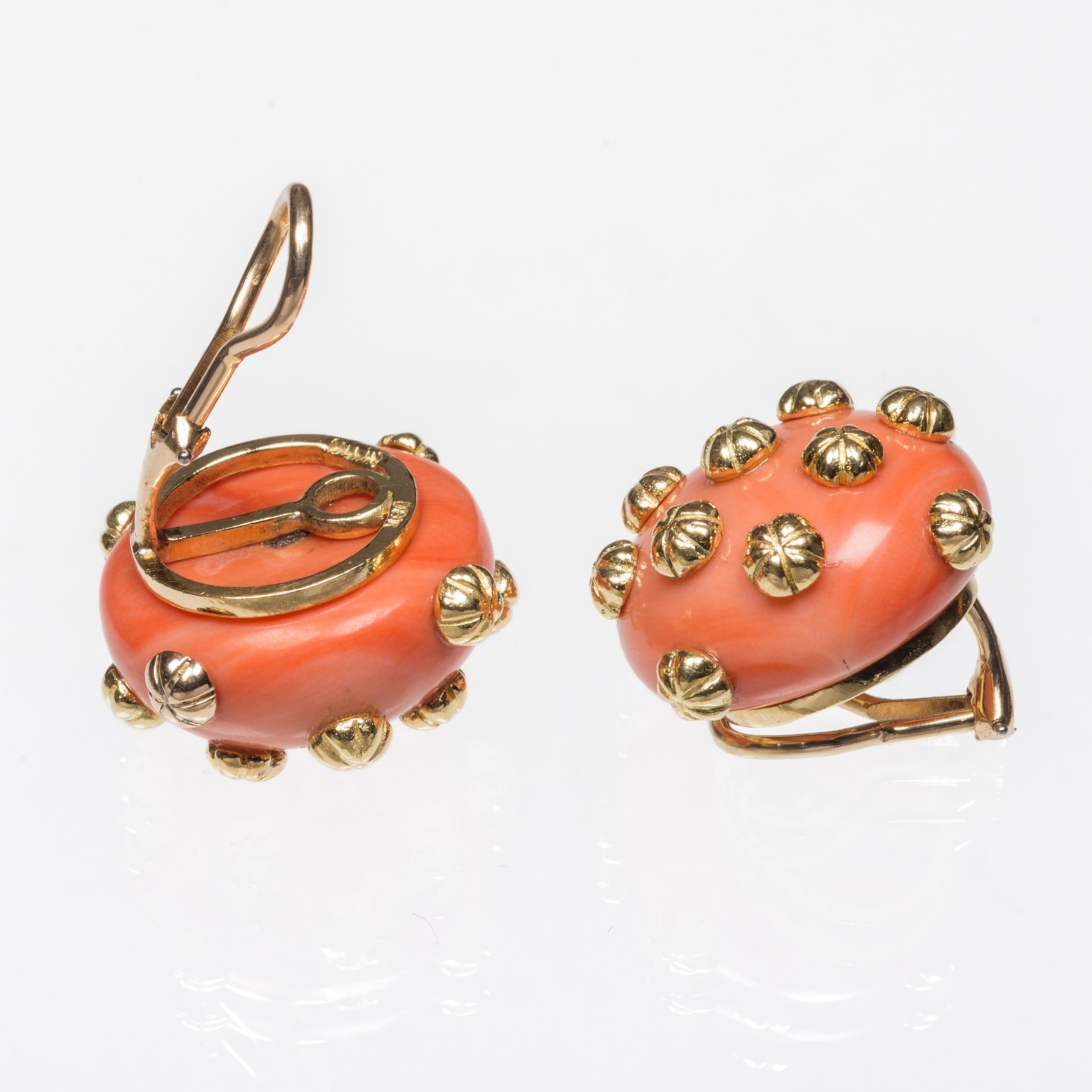 These stylish and elegant earclips are made out of 18 kt gold and large coral buttons decorated with golden rivets. The coral has a beautiful bright orange hue and a lovely shine. 
