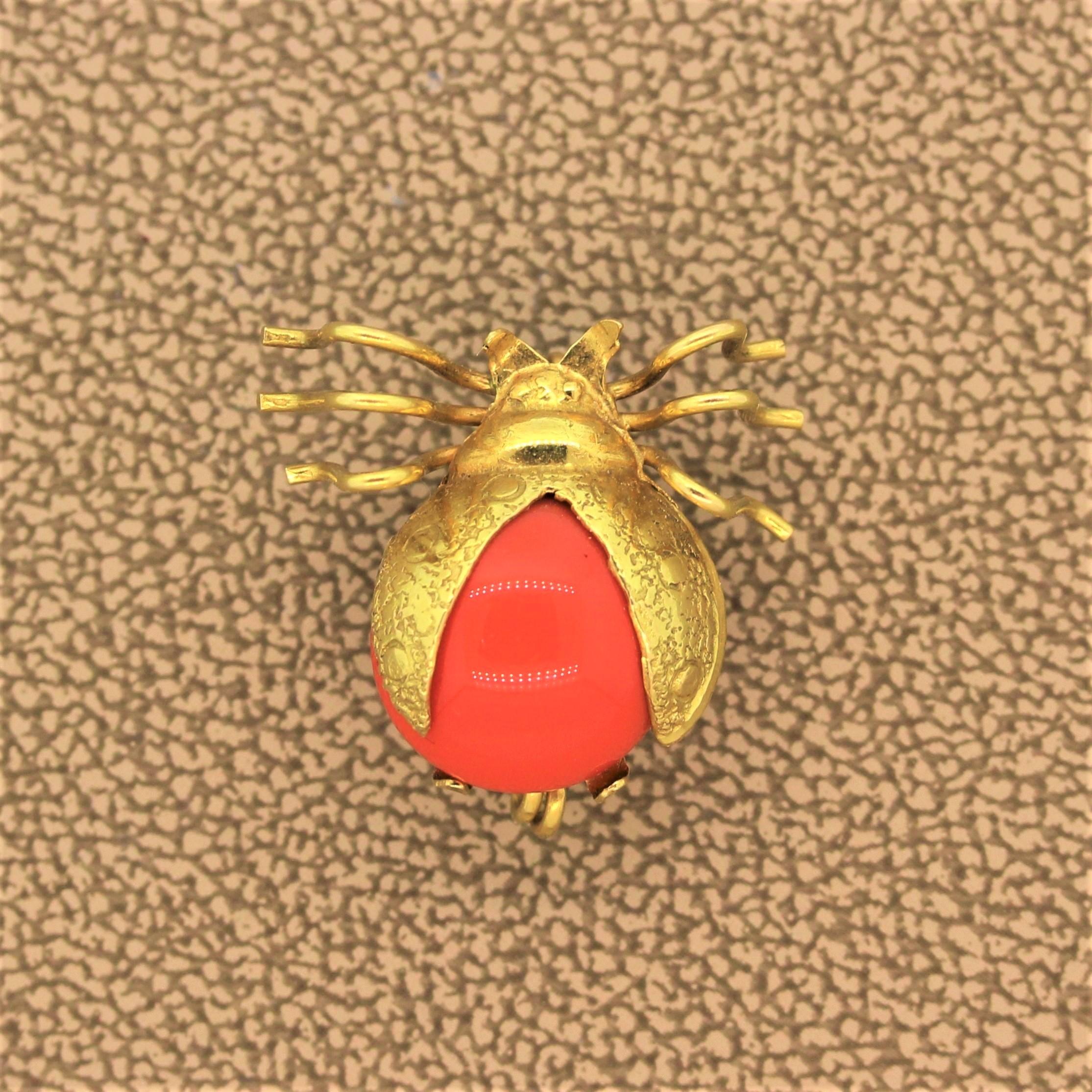 ¡Mariquita! Una dulce mariquita reptante con las alas desplegadas lista para emprender el vuelo. Esta pieza sirve también como colgante para llevar en el pecho. El cuerpo es de coral cabujón con oro amarillo de 18 quilates utilizado para las alas