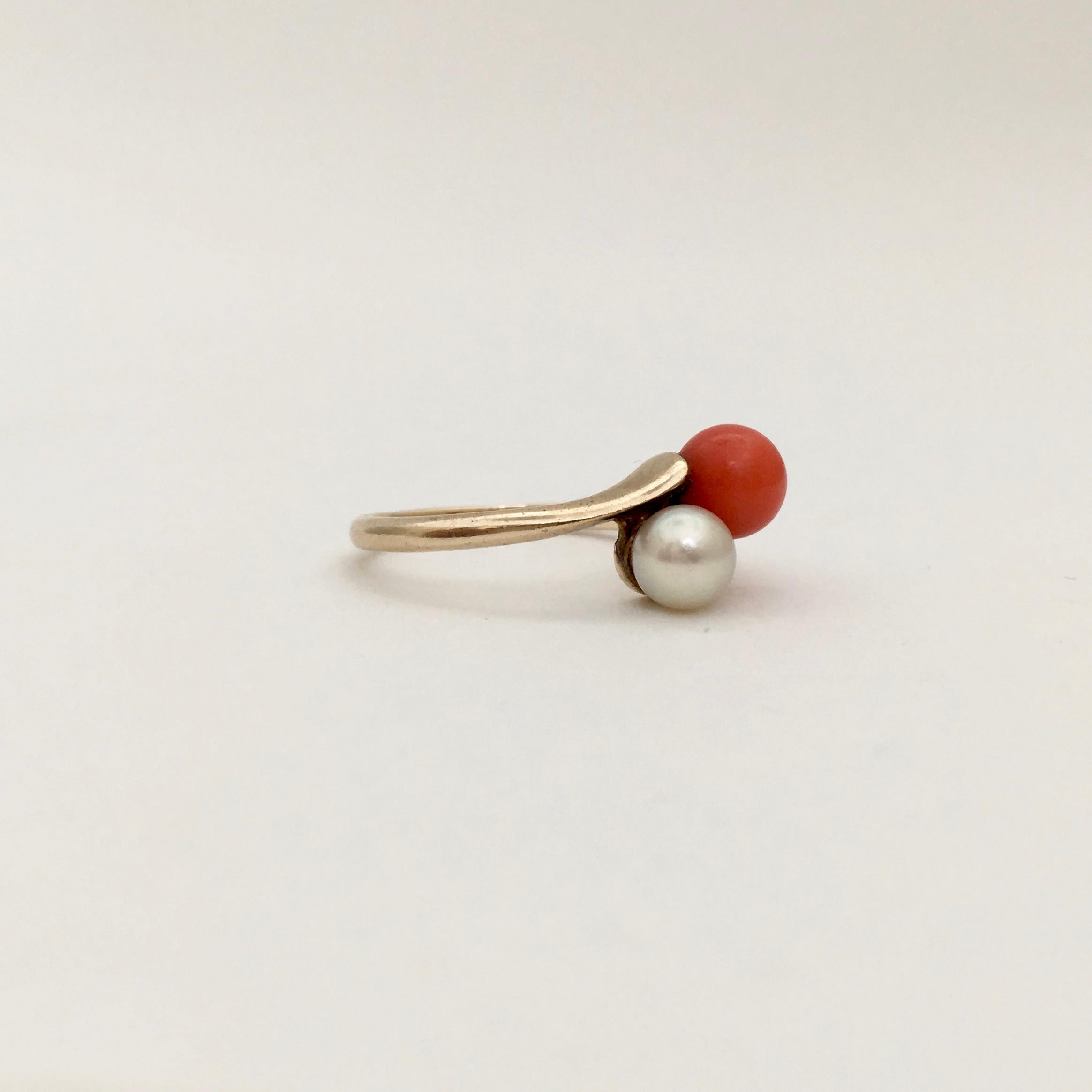 This stylish coral and pearl bypass ring has a Mediterranean air. The combination of red coral and white pearl makes a striking contrast, which is eye-catching and modern. The ring does not have a date stamp, but probably dates from the 1960s or