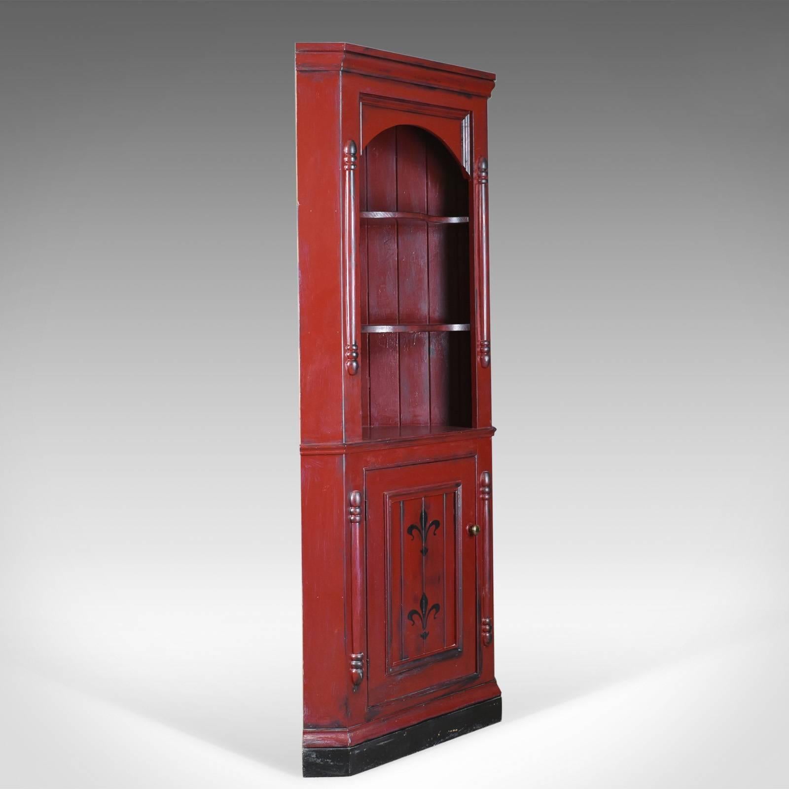 This is a vintage corner cabinet, a late 20th century painted pine cupboard.

Attractively finished in an aged rouge paint
Waxed and polished for protection

A pair of serpentine shelves to the upper cabinet
A field panel door decorated with