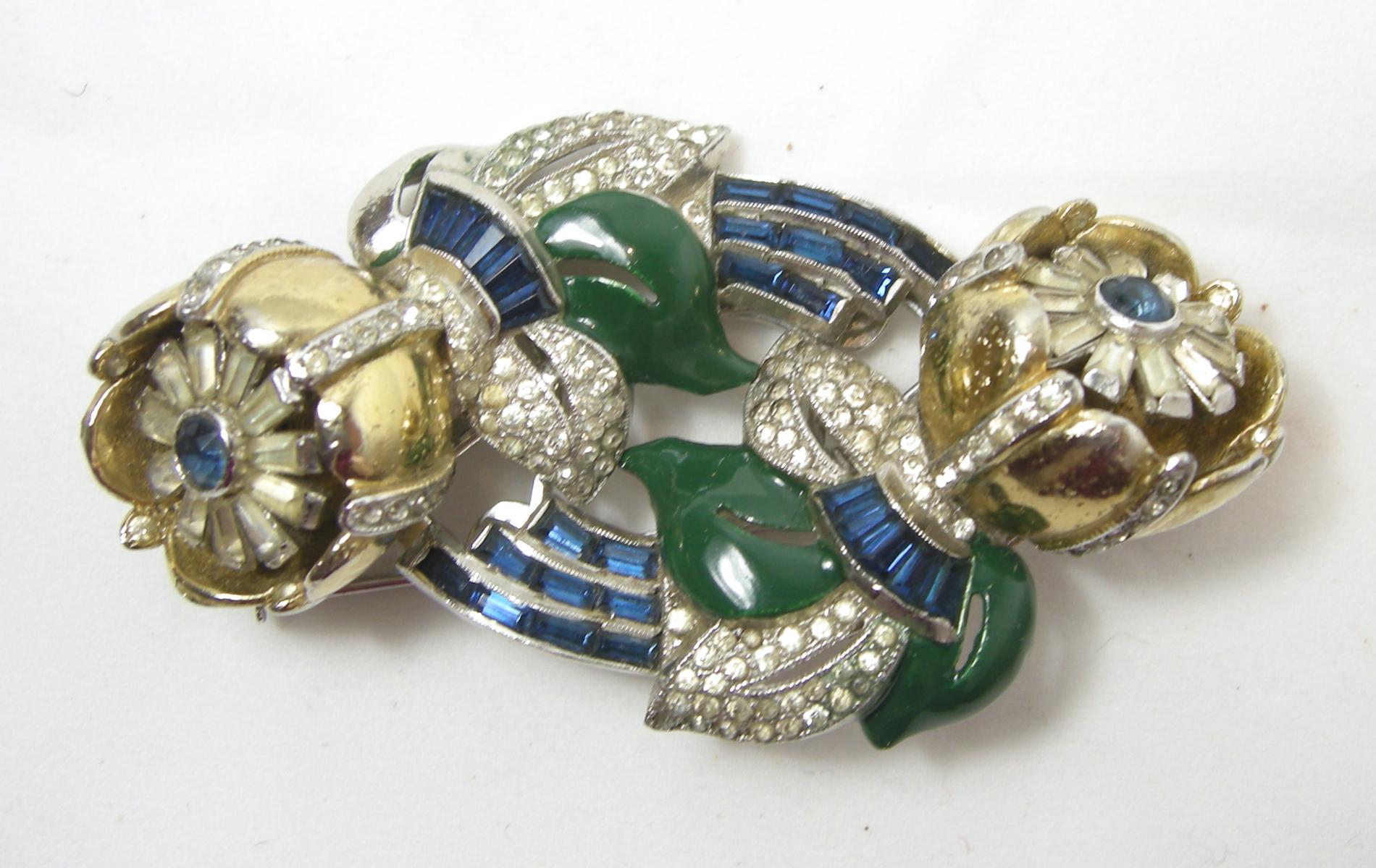 This vintage Coro duette & earrings has the famous trembler floral design with blue and clear crystal with green enameling in a gold tone setting.  The screw-clip earrings measure 7/8” diameter and the duette brooch is 3” x 1-3/4”.  This vintage