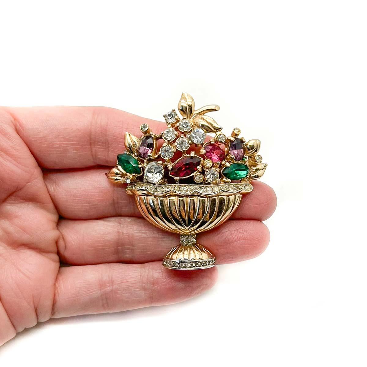 A Vintage Coro Giardinetti Basket Brooch. Crafted in lustrous gold-plated metal and set with clear and gem coloured glass crystals. A Giardinetti brooch features intricate floral motifs set in a vase or basket. The term Giardinetti meaning 'little