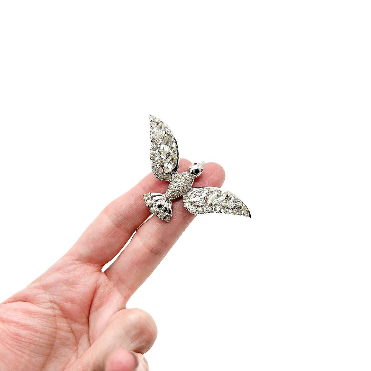 A Vintage Coro Bird Brooch. One of Coro's most delightful figural designs. A bird in flight in rhodium plated, solid sterling silver set with sparkling fancy cut and chaton crystals. Eye catching and utterly timeless.
The jewellery company 'Coro'