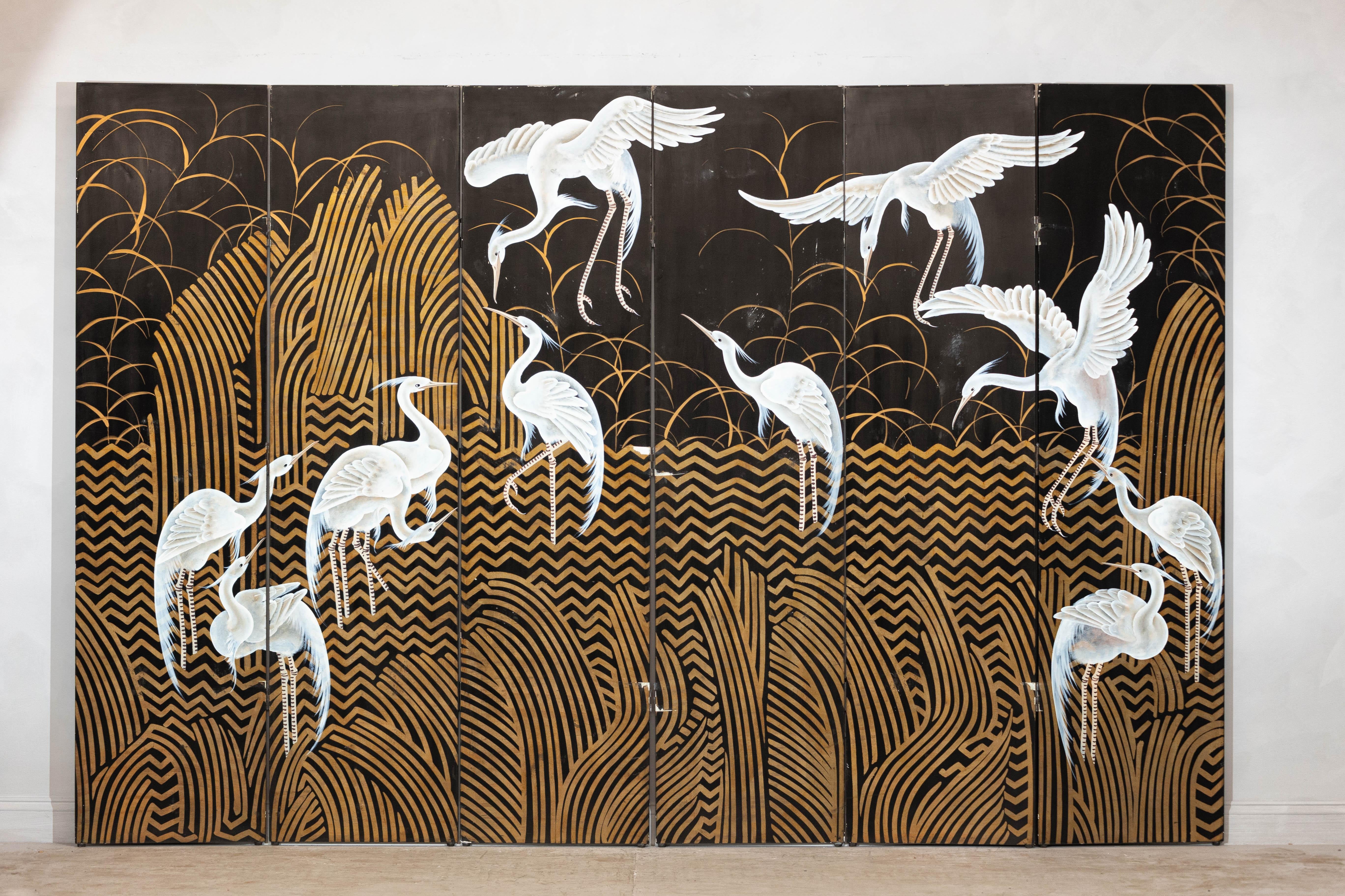 A vintage Chinese six-panel Coromandel screen, adorned with hand-painted cranes and intricate gilt accents, showcasing a harmonious balance of natural beauty and artistry. The screen’s black lacquered backdrop is adorned with delicate golden reeds
