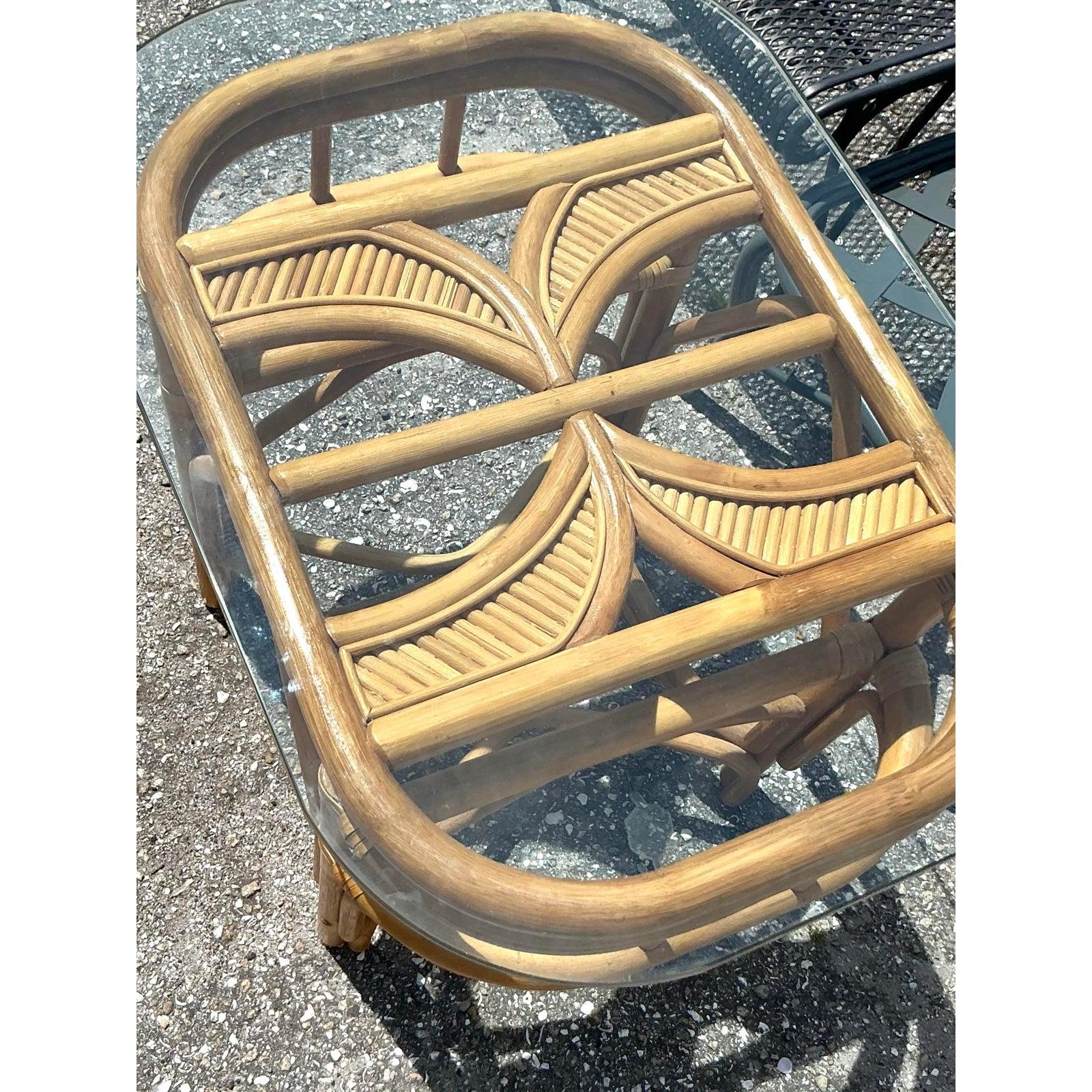 Enhance your living space with this charming pair of vintage coastal bent rattan side tables. Each table showcases exceptional craftsmanship, featuring gracefully curved rattan and bamboo frames that create an airy, open silhouette. The design